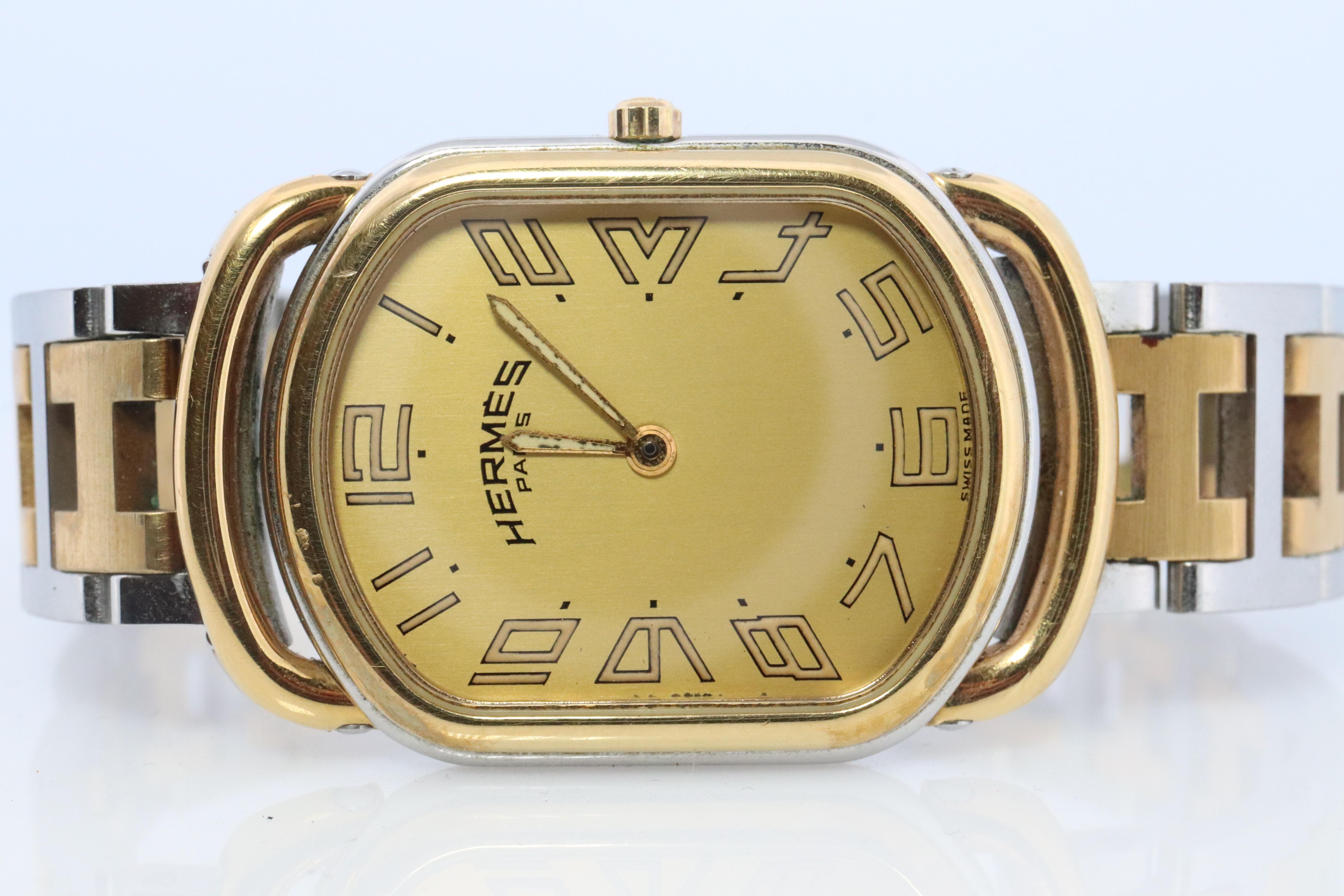 This is an authentic HERMES Stainless Steel 25mm by 31mm Rectangle Oval Rallye Quartz Watch Champagne. 

The watch is crafted of stainless steel and plated 18k Gold. features a champagne dial, gold hands and hour markers, two tone link bracelet,