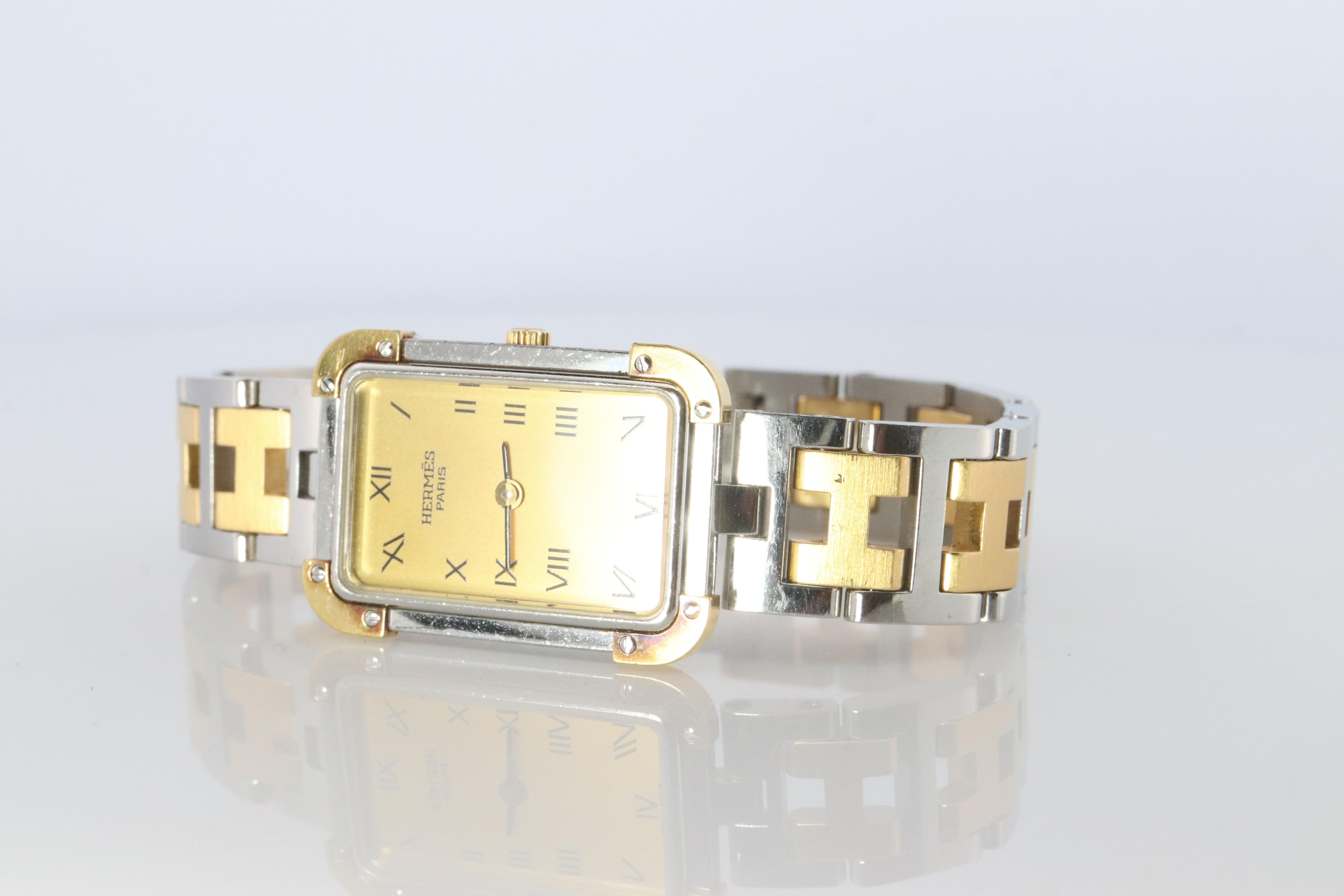 Dies ist eine authentische HERMES Edelstahl 24mm Rechteck Croisiere Quarzuhr Weiß. Die Uhr ist aus Edelstahl gefertigt und verfügt über ein champagnerfarbenes Zifferblatt, schwarze Zeiger und Stundenmarkierungen, ein zweifarbiges Gliederarmband,