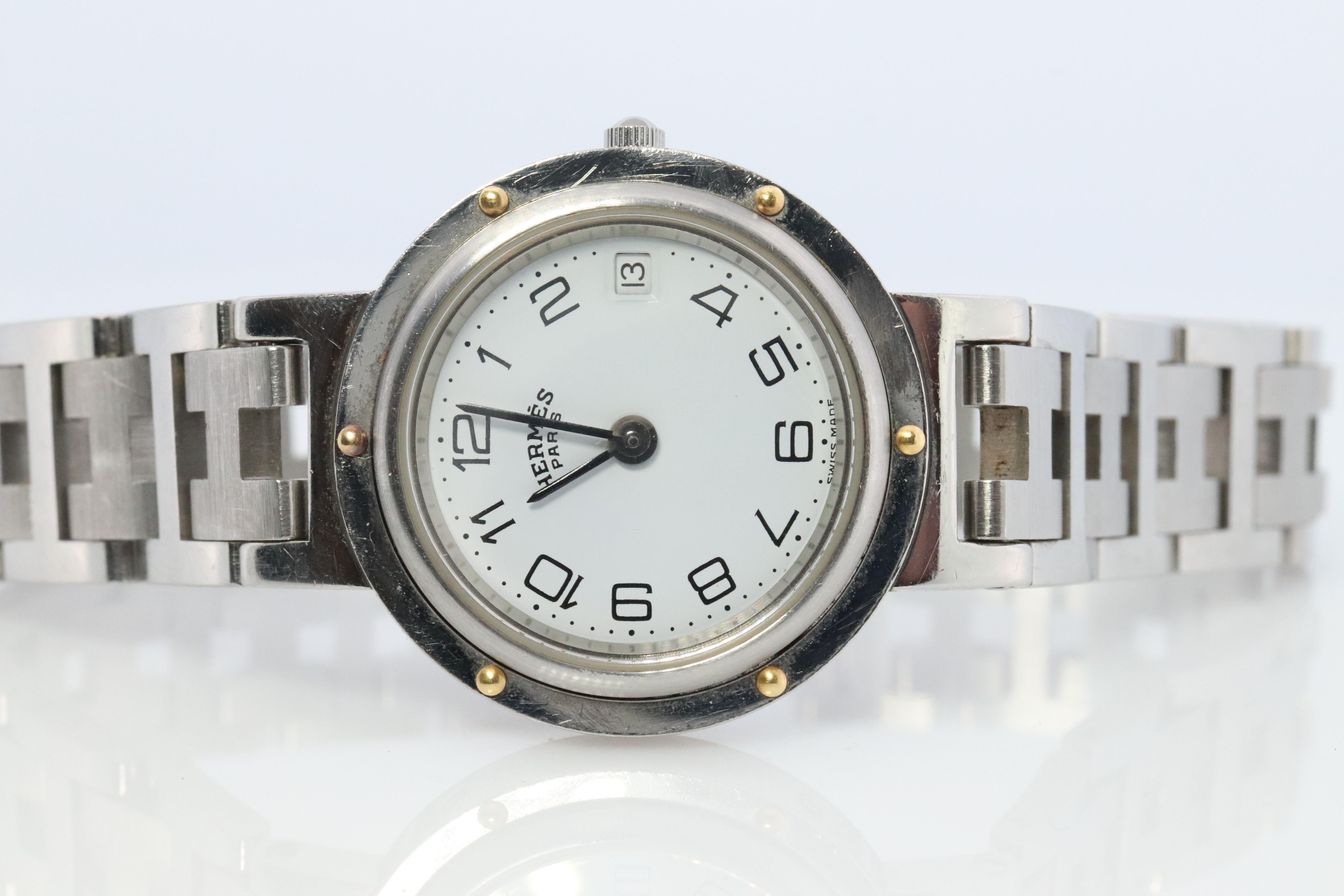 This is an authentic HERMES Stainless Steel 24mm Round Clipper Quartz  White. The watch is crafted of stainless steel and features a white dial, black hands and hour markers, Silver  tone link bracelet, sapphire crystal, and a quartz movement.

ref