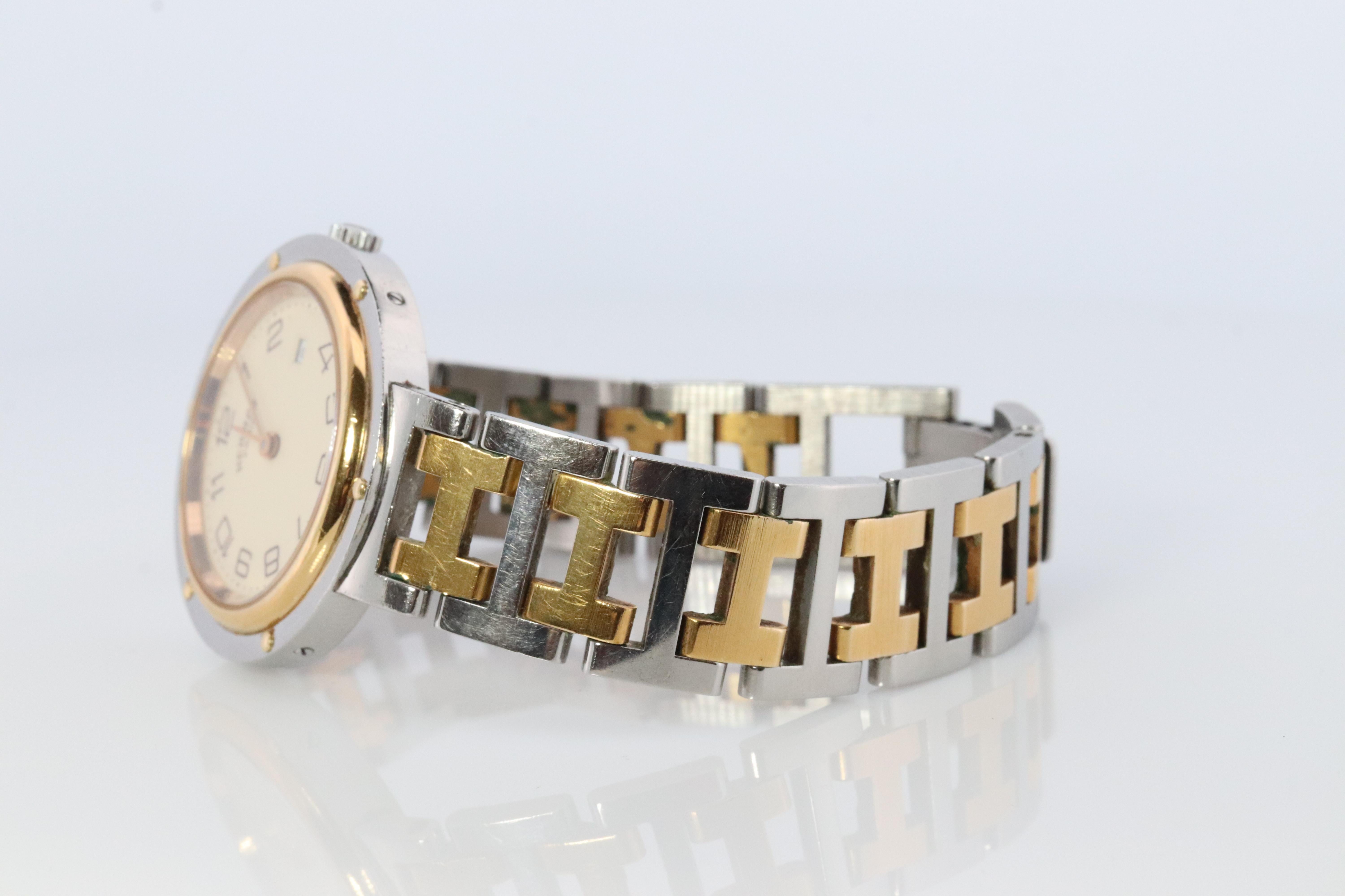 This is an authentic HERMES Stainless Steel 30mm Round Clipper Quartz Cream White. The watch is crafted of stainless steel and features a white dial, gold hands and hour markers, two tone link bracelet, sapphire crystal, and a quartz