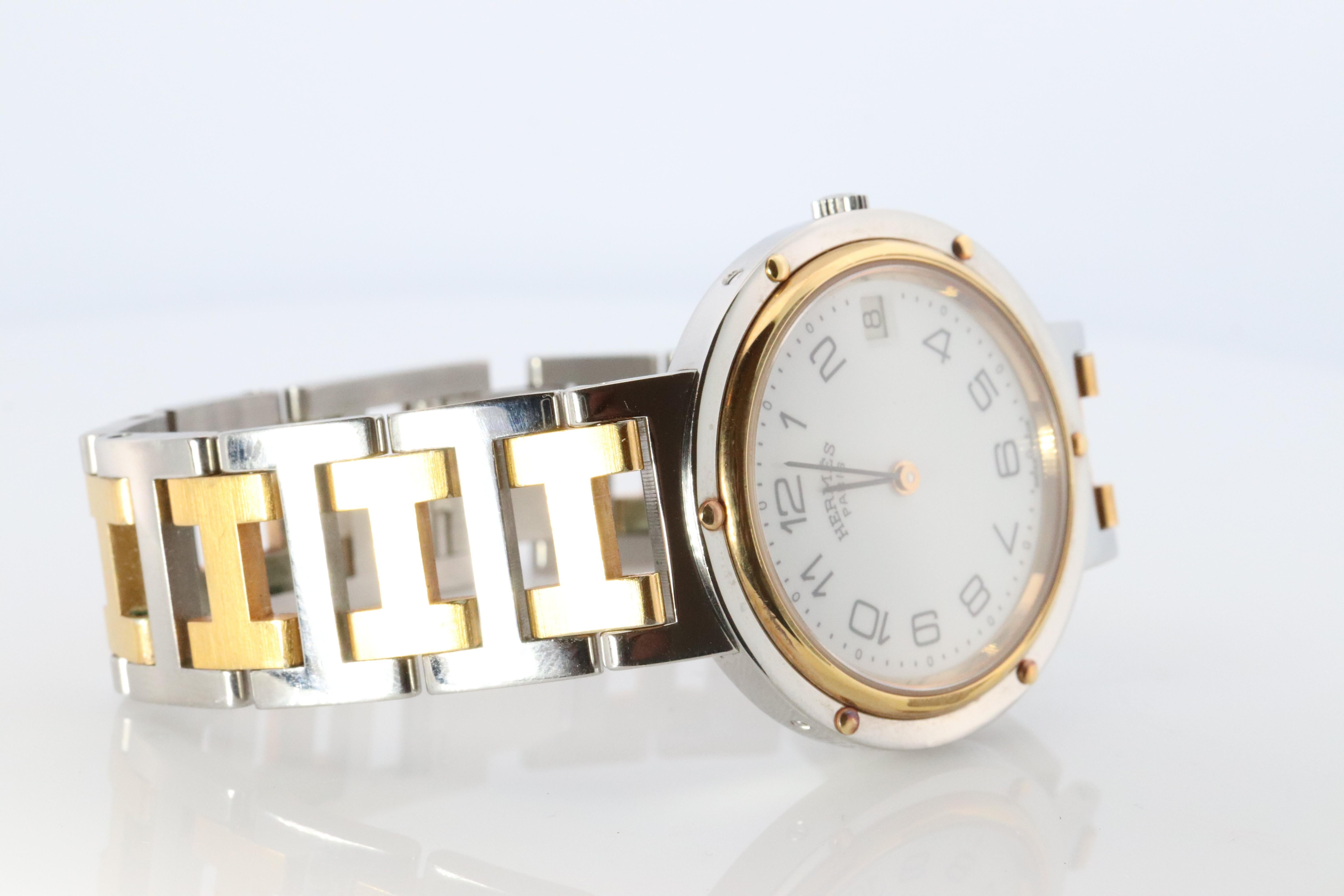 This is an authentic HERMES Stainless Steel 

ref.CL4.210

30mm Round Clipper 
White Dial.
Quartz New Battery replaced.

The watch is crafted of stainless steel and features a white dial, gold hands and hour markers, two tone link bracelet, sapphire