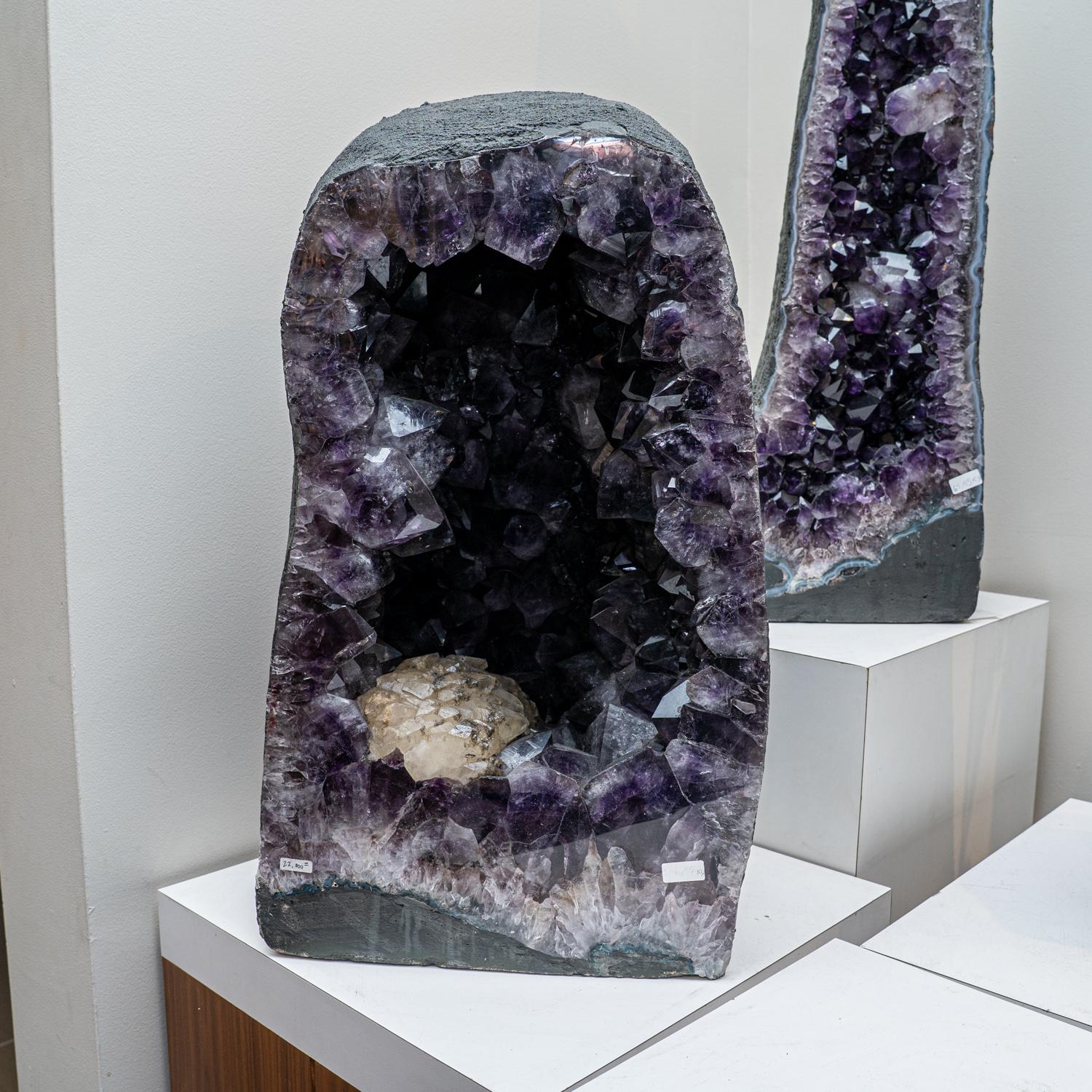 Esta auténtica Geoda de Racimo de Amatista de Brasil es una formación natural de primera calidad de amatista gema adornada por pequeños cristales lisos de calcita. El adorno catedral semigeoide muestra brillantes cristales totalmente terminados con