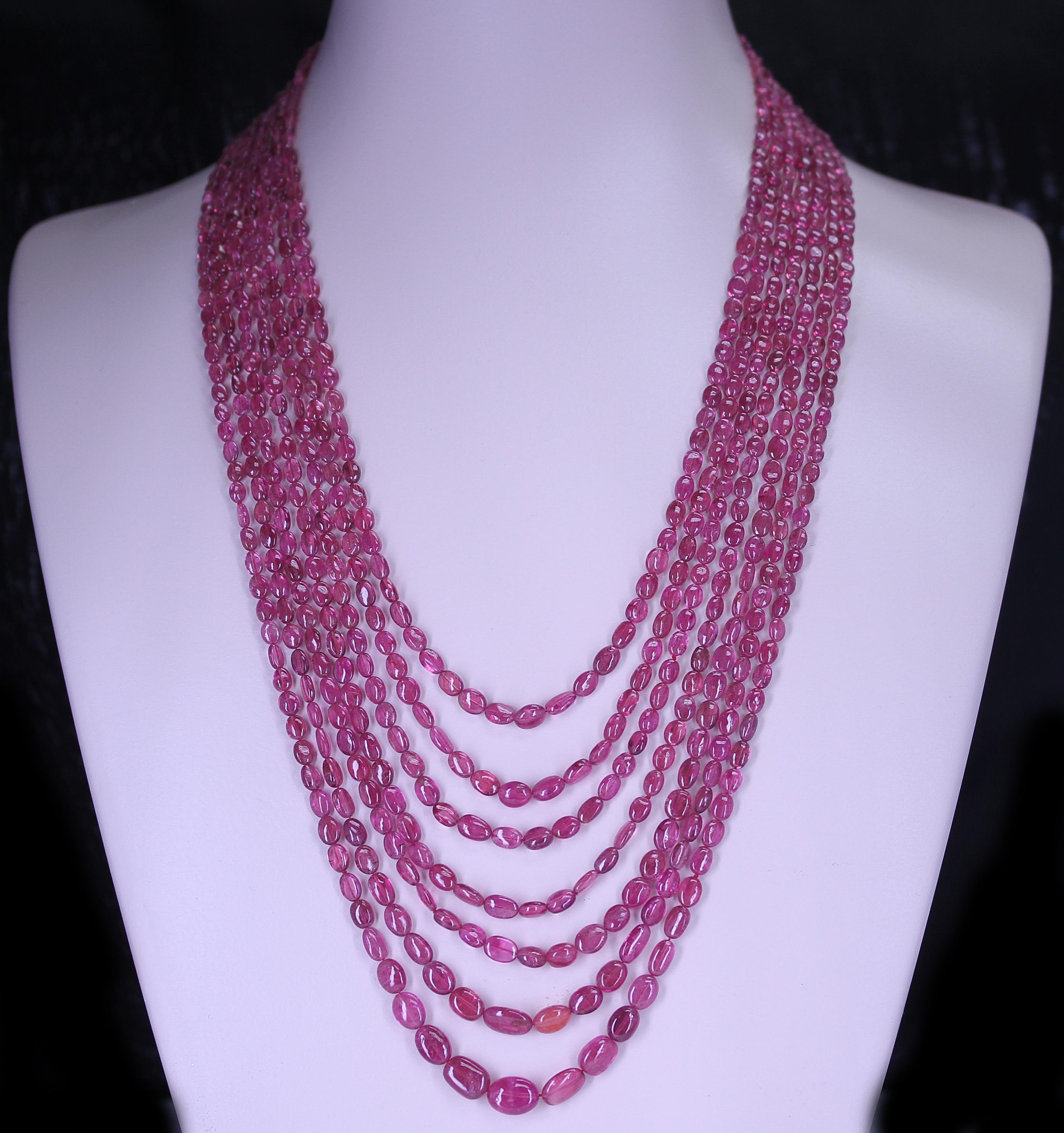 A Genuine & Natural Smooth Pink Tourmaline Small Tumbled Beads Necklace with 7 Lines, weighing 514 carats. The clasp is 14K Yellow Gold, and the length of the strands range from 23