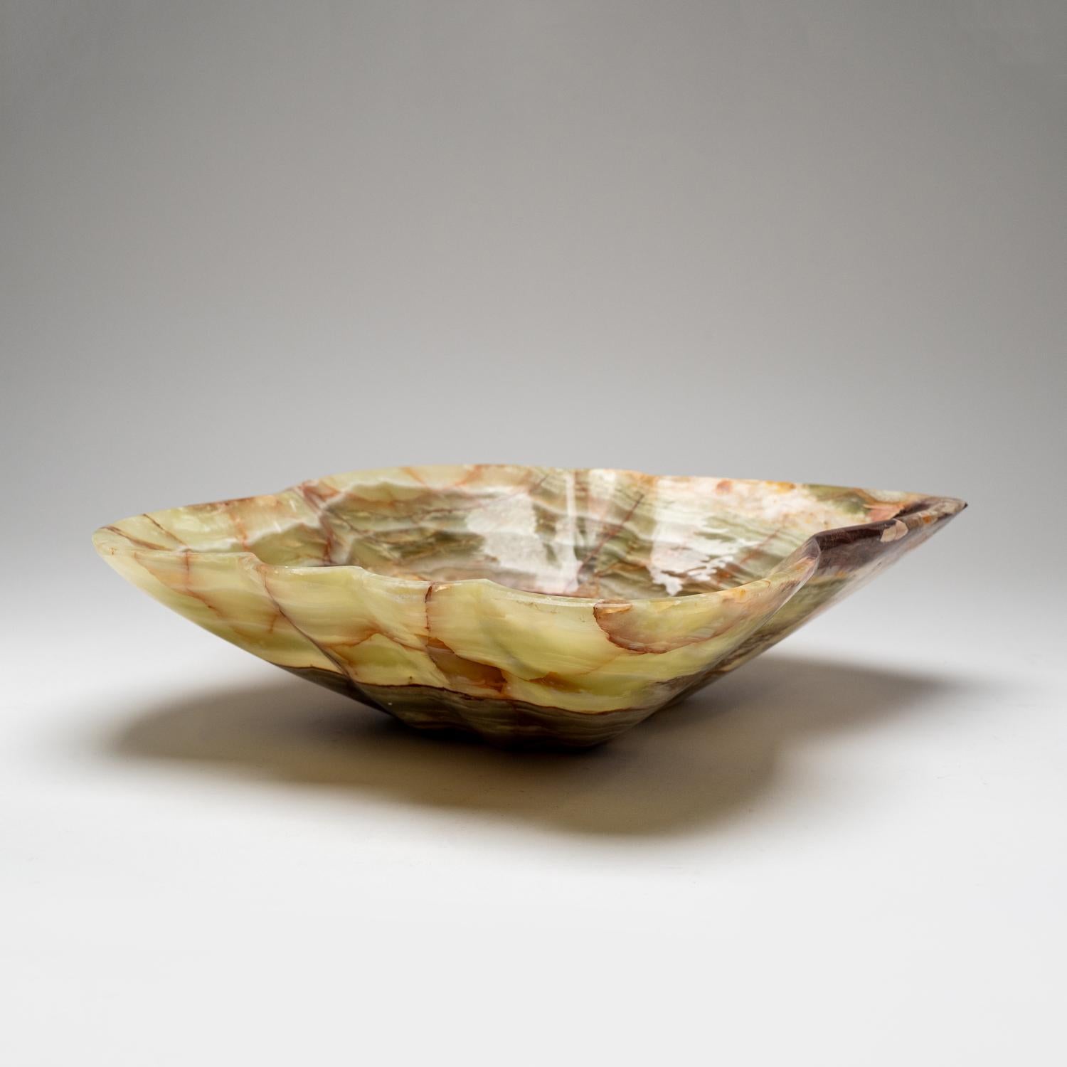 Diese einzigartige dekorative Schale in freier Form, die aus einem einzigen Stück natürlichen Onyx gefertigt ist, besticht durch ihre hochglanzpolierte Oberfläche und ihre satten, erdigen Farbtöne, die Weiß-, Honig- und Brauntöne mischen. Mit seinem