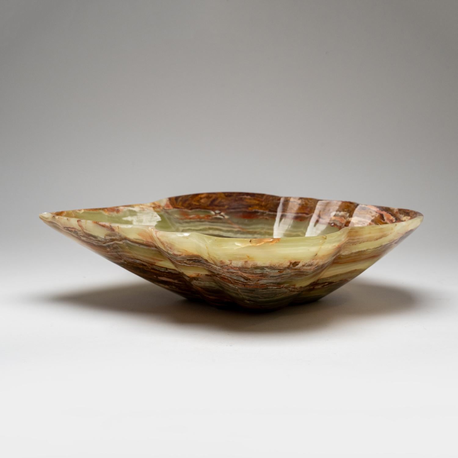 This unique free-form decorative bowl, constructed from a single chunk of natural onyx, features stunningly polished mirror finish and rich, earthy tones that blend white, honey and brown shades. An ideal centerpiece with its captivating translucent