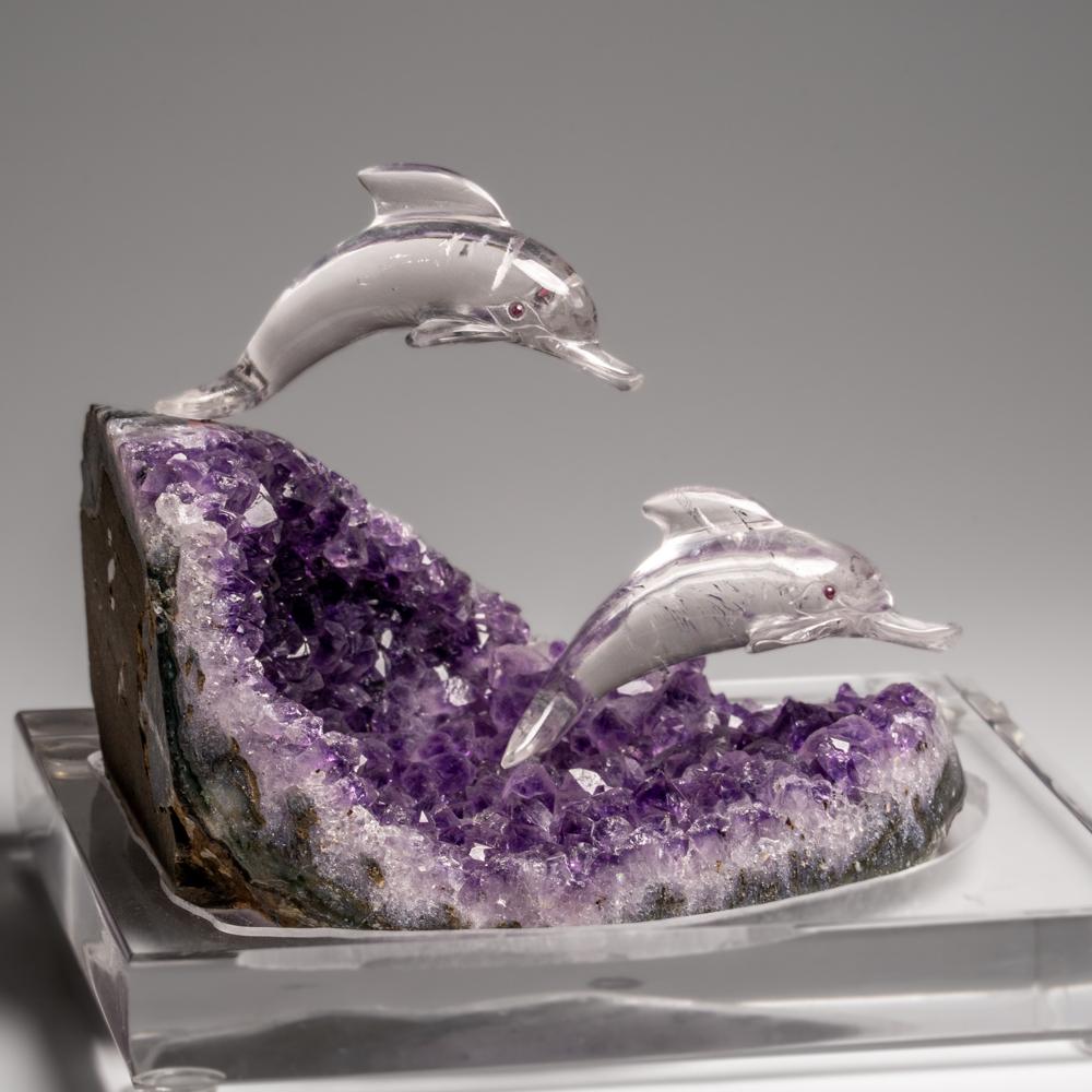 This Hummingbird carving is a unique piece of art, carved from museum-quality clear quartz two dolphin, with garnet eyes. The dolphins is perched atop an amethyst geode matrix and mounted on a custom stand for convenient display. This sculpture is