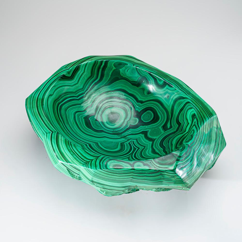 This Genuine Polished Malachite bowl is meticulously crafted and features intricate concentric growth patterns. Sourced from Zaire, it has no fill and boasts powerful balancing and manifesting properties. A prized stone in the metaphysical realm,
