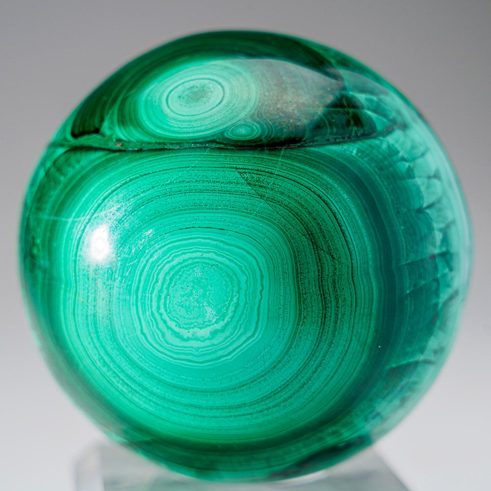 This genuine polished Malachite Sphere (2.25 lbs) is sourced from Zaire and features a well-defined green banded pattern. It is solid material with no fill and comes with an acrylic display stand. Known for its balancing and transformative