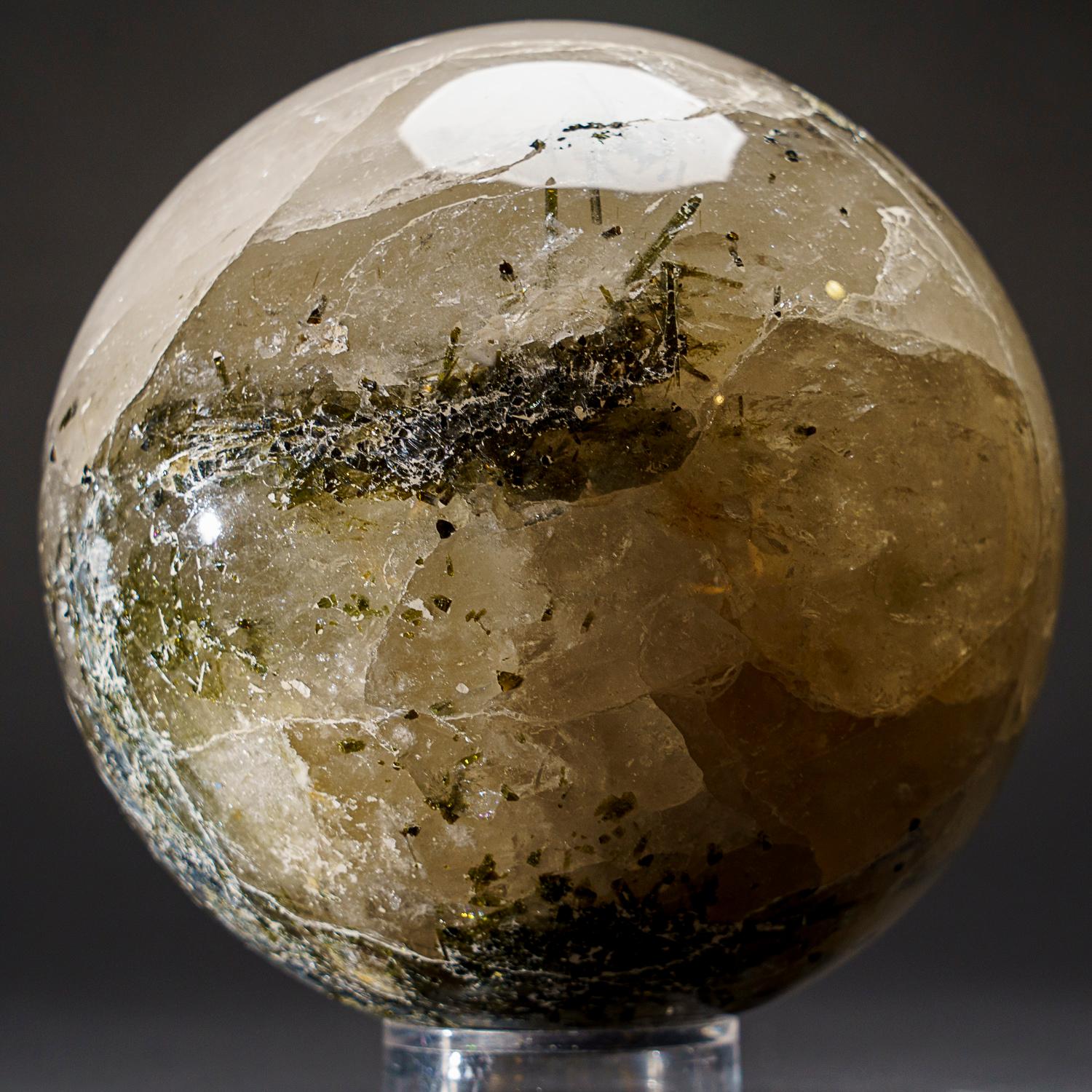 This Genuine Polished Quartz with Tourmaline Sphere boasts impressive transparency and a smooth, reflective finish due to careful hand polishing. By combining the grounding properties of Quartz with the protective energies of Tourmaline, this sphere