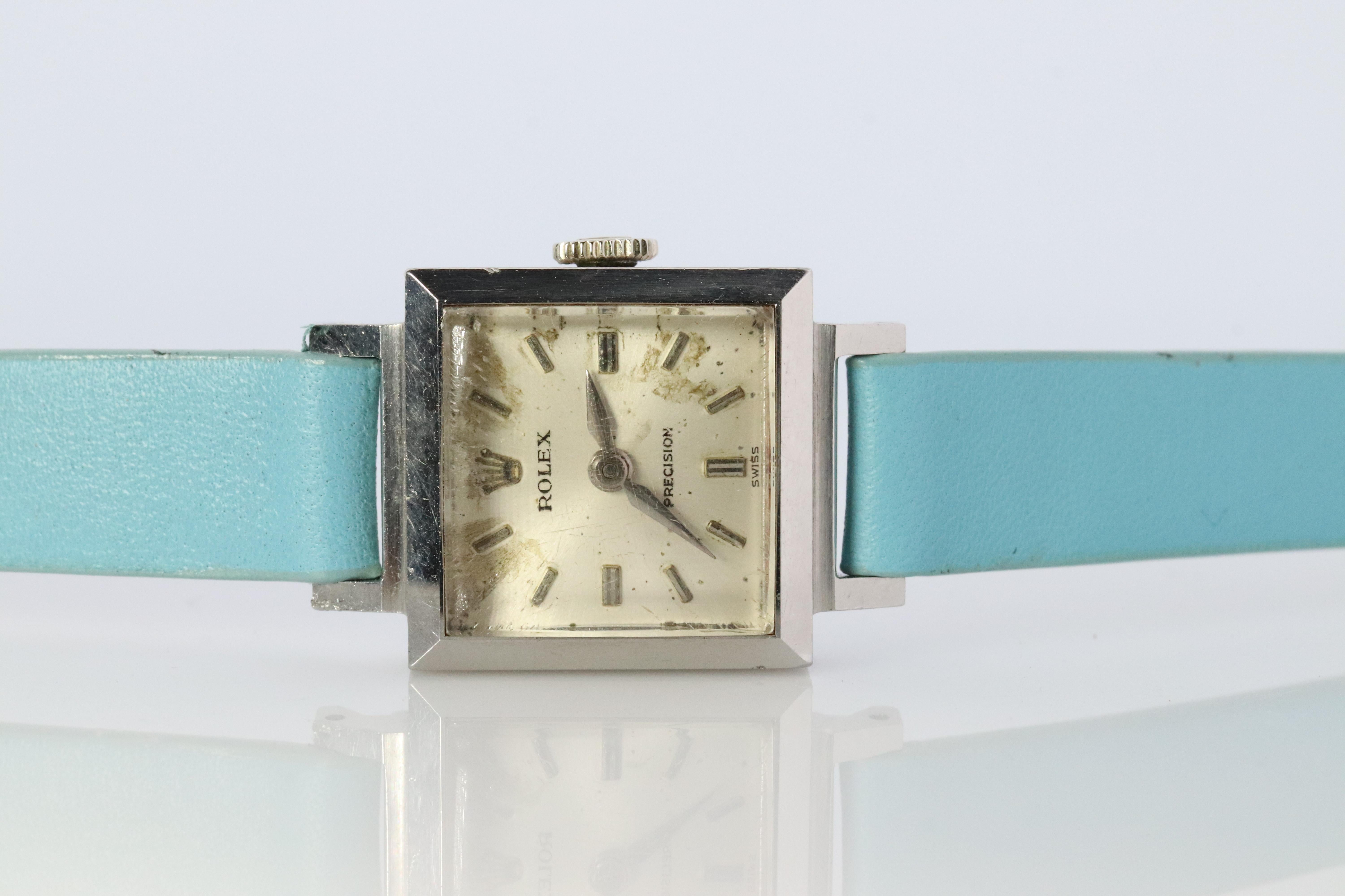 Stainless Steel Rolex Precision Ladies mechanical Movement Wristwatch. Circa 1966. 

1400 Caliber Rolex Movement Ref. 3408.

Beautiful Watch. Manual Windup mechanism. 

Case is Stainless Steel
New Light blue leather band.

18mm by 18mm square