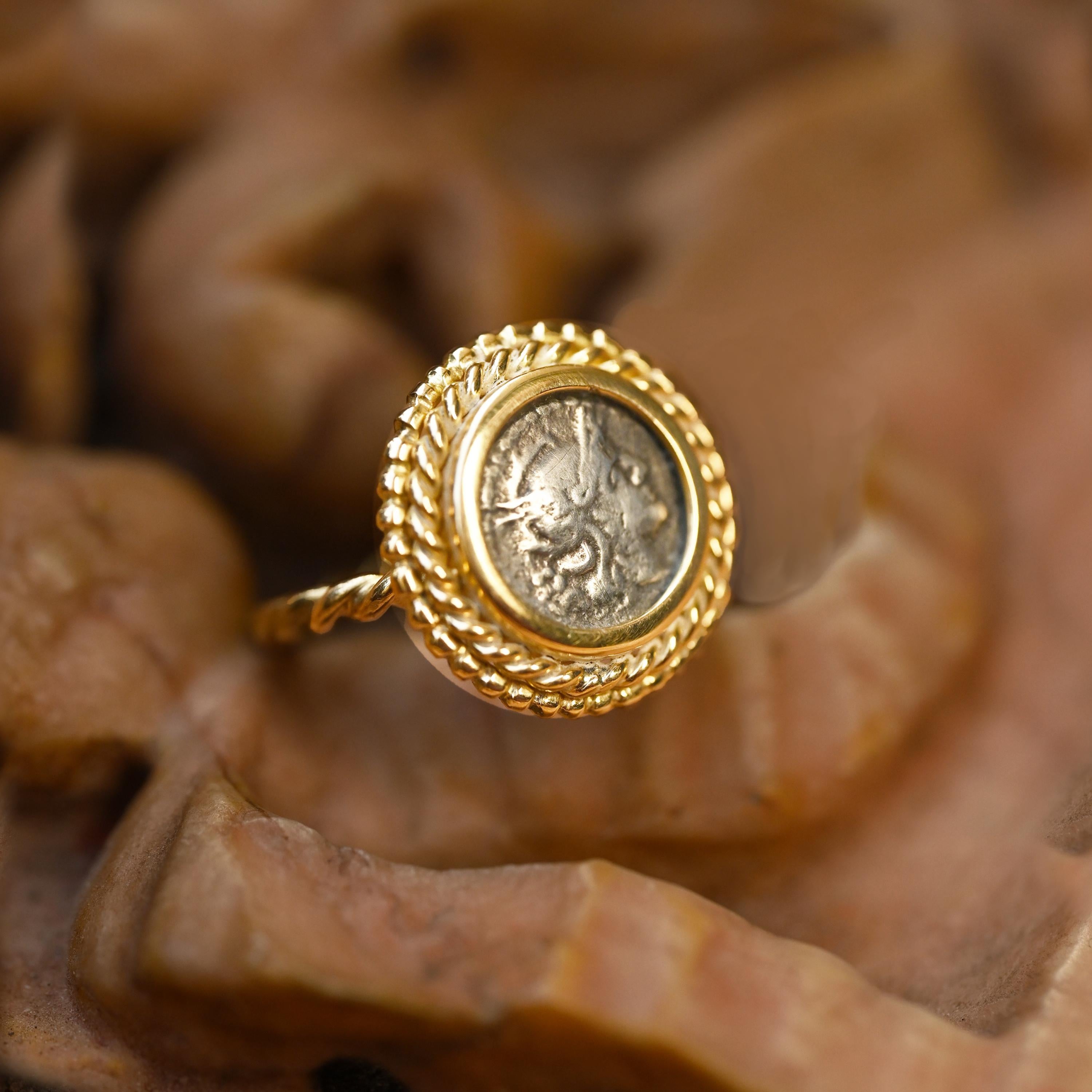 This stunning 18 kt gold ring showcases an authentic silver Roman coin, specifically a sestertius from 211 BC, featuring a depiction of the Goddess Rome. Meticulously crafted, this ring is a testament to artistic skill and attention to detail. The