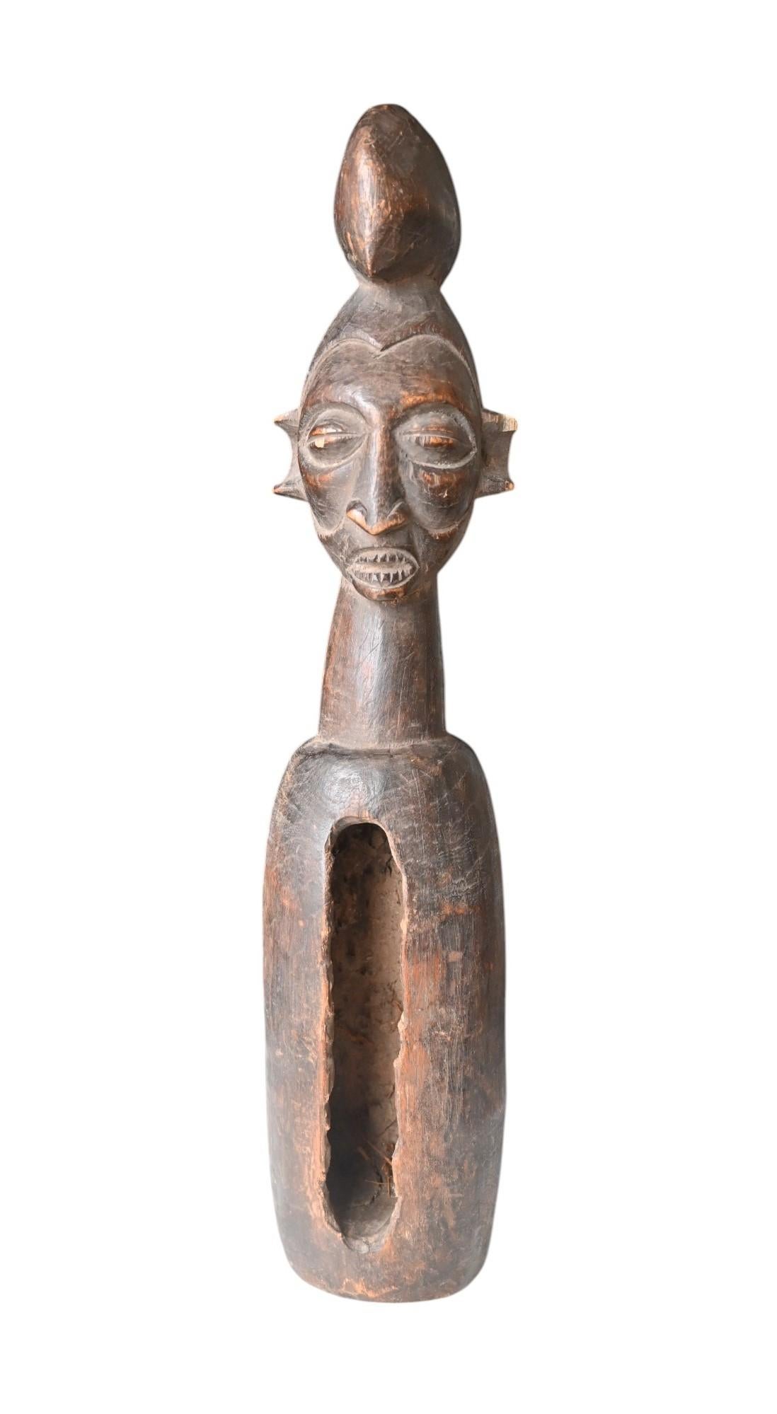 Tambour à fente Yaka du début du 20e siècle, sculpté à la main, représentant une tête qui, lorsqu'elle est frappée, est censée servir de bouche à la voix de l'oracle. Chez les Yaka, cet instrument symbolique est appelé 