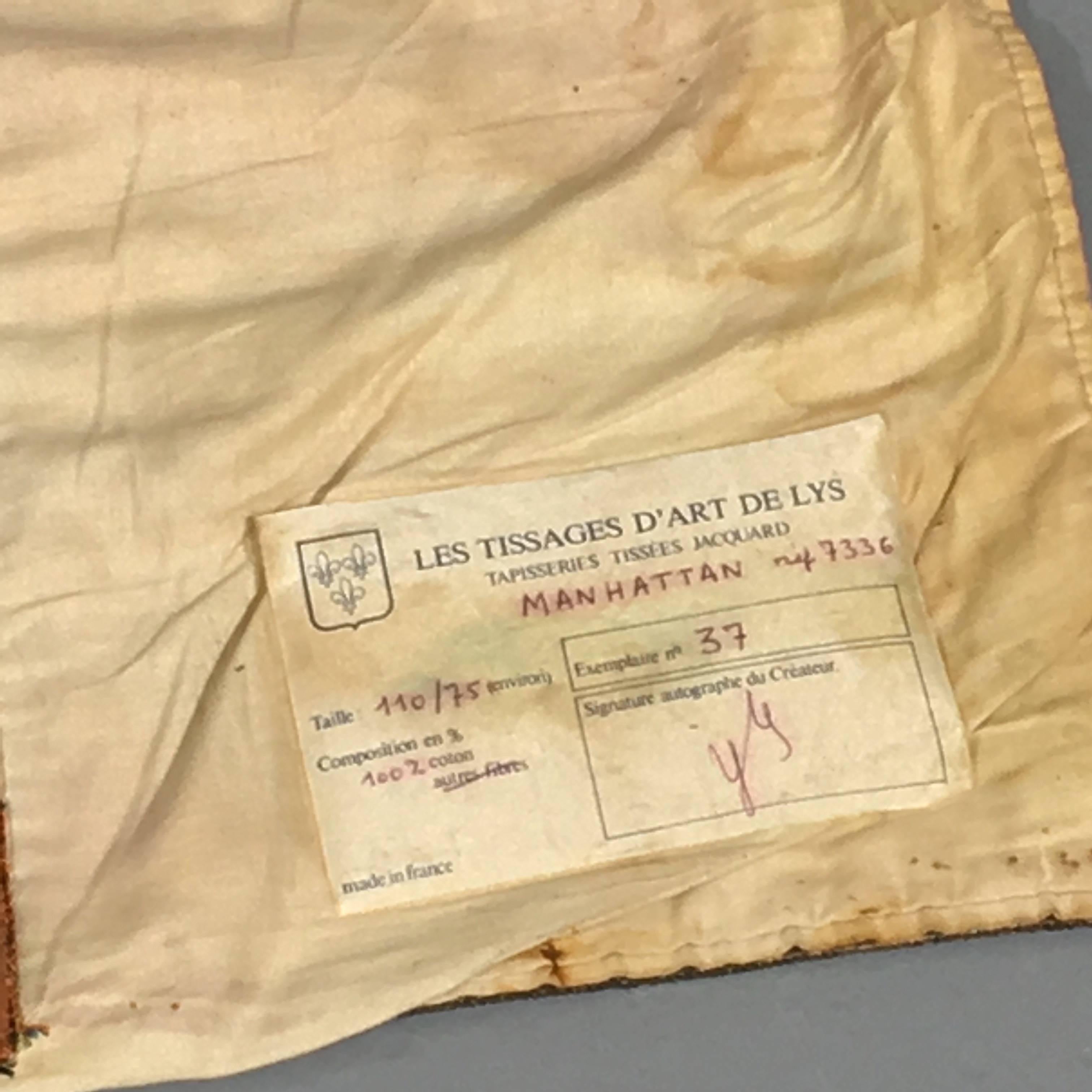The signature of the artist is not visible. The name of the tapestry is Manhattan. Tapisserie tissées jacquard. Jacquard was the name of the ingenior who inventic the mechanic process to make tapestry. It 100ù made in France, and the manufacturer