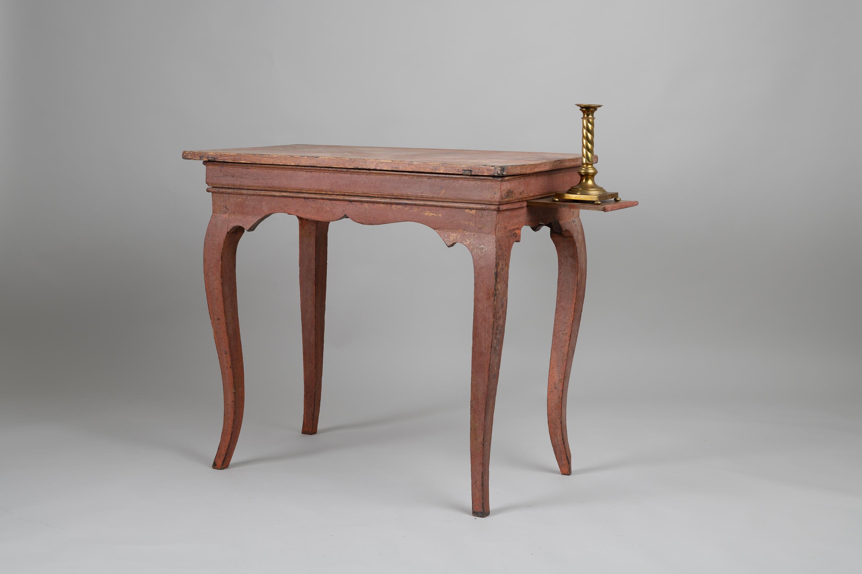 Rococo table of the period during the late 1700s from Sweden. The table has a profiled rim with curved legs and extendable candle trays on the short ends. These trays are for candles to light the table top when seated at the table. Underneath the