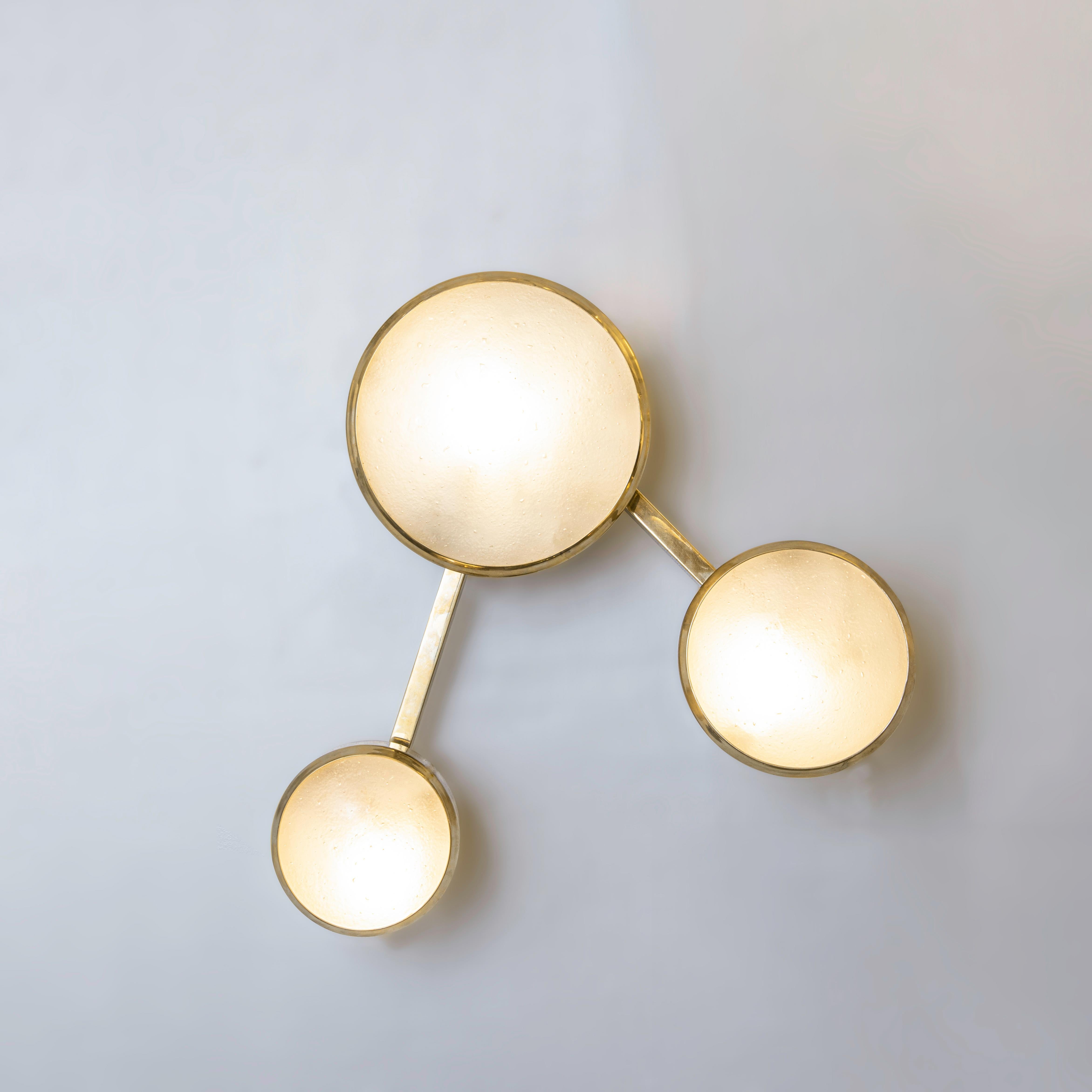 El aplique Geo presenta tres pantallas de cristal de Murano de distintos tamaños sobre un marco articulado de latón que puede ajustarse fácil y rápidamente para crear distintas configuraciones. Se muestra en latón pulido sin lacar con nuestro