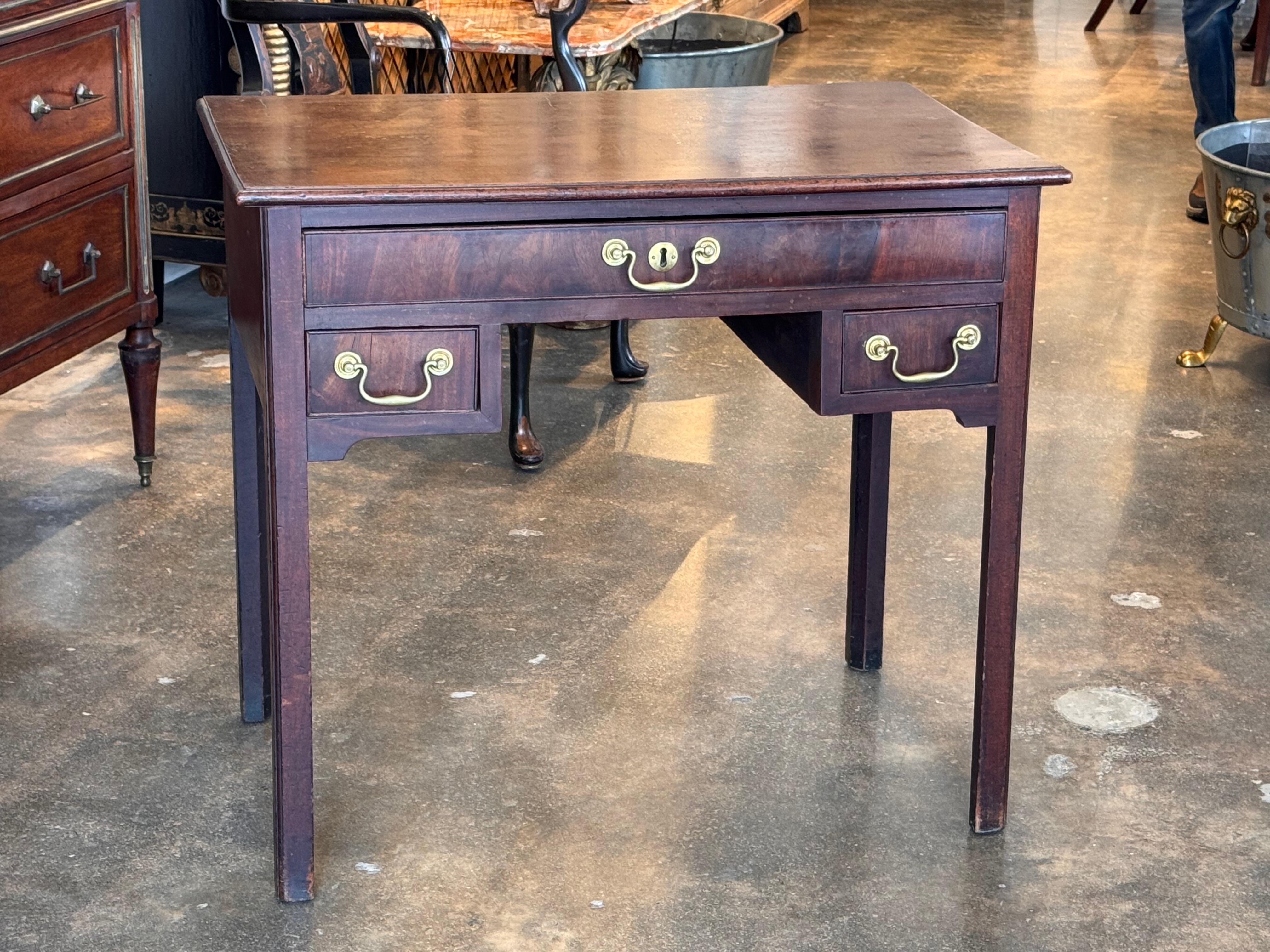 Un elegante mobile basso con una superficie in legno riccamente patinata e una classica ferramenta in ottone. Il design raffinato comprende un cassetto centrale affiancato da due cassetti più piccoli, che offrono funzionalità e fascino senza tempo.