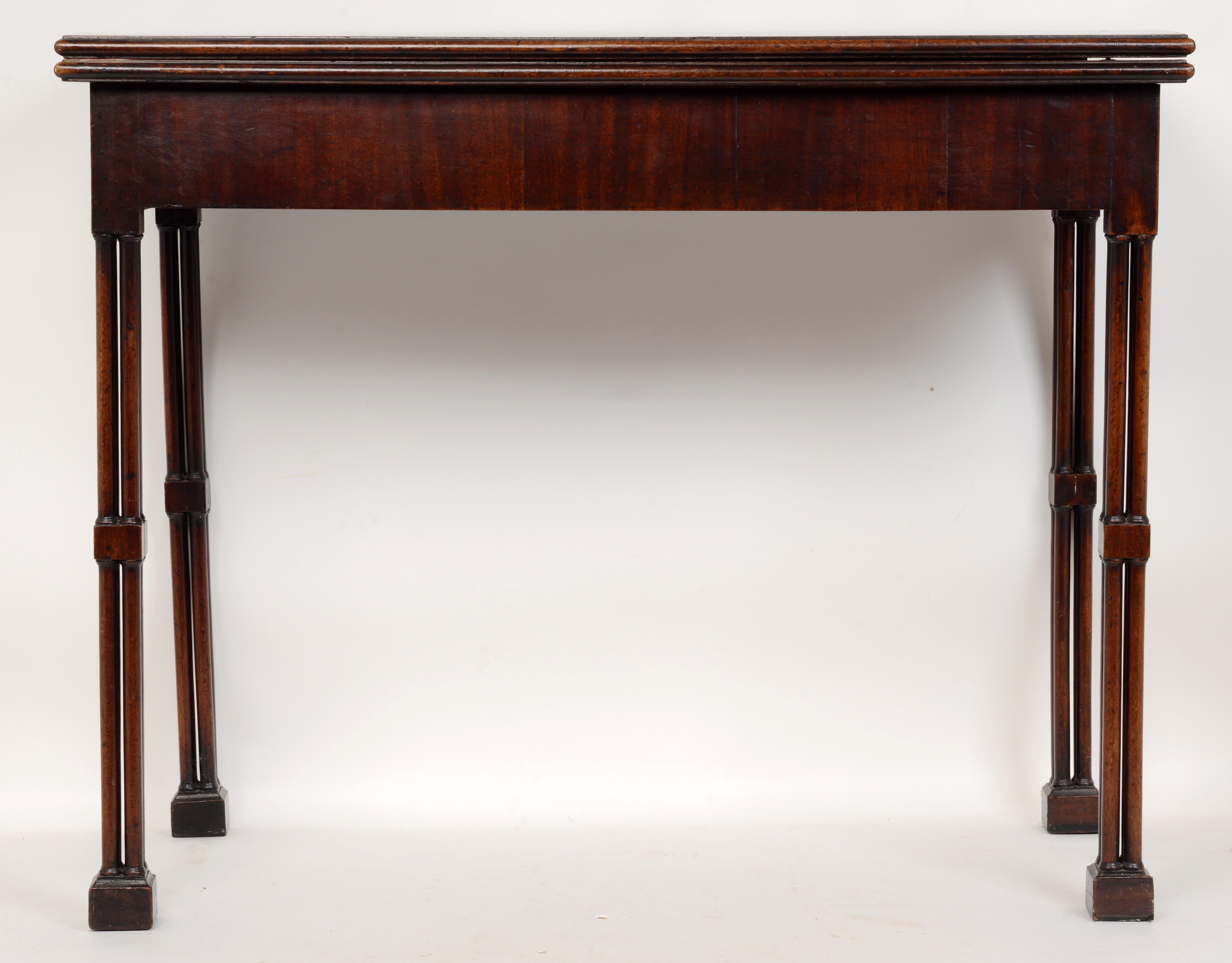 Geo III Mahogany fold-over card table with cluster-leg and concertina action c1780. The hinged Leather lined and gilt tooled top opens and is supported by hinged, concertina-action rear legs. The table is raised on cluster turned and caged legs with