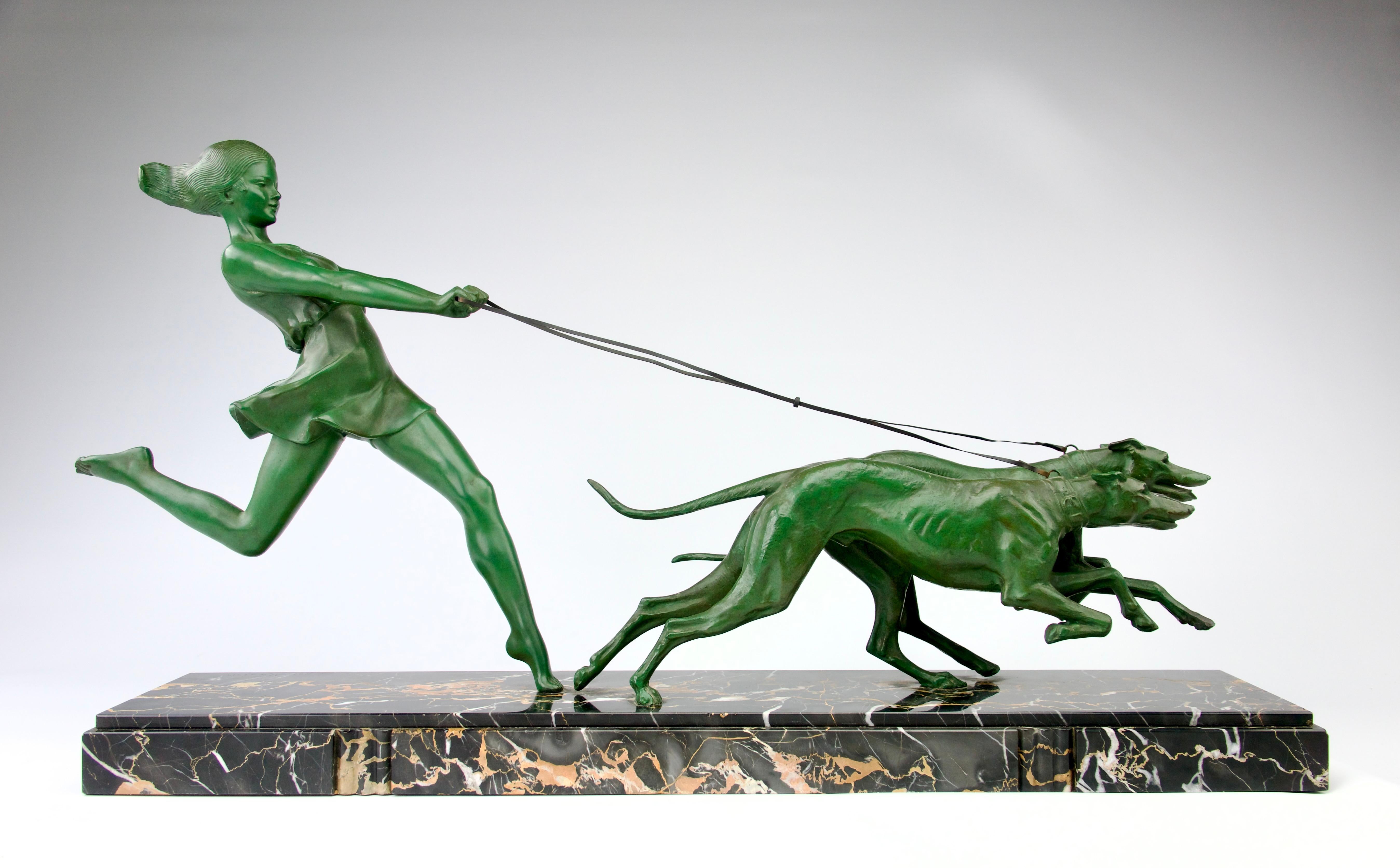 Superb and rare art déco sculpture by Géo Maxim (1885-1940) representing a woman running after her greyhounds. Beautiful green patina on the regula affixed to a superb black and orange veined Portor marble base. France, 1930s.

In excellent