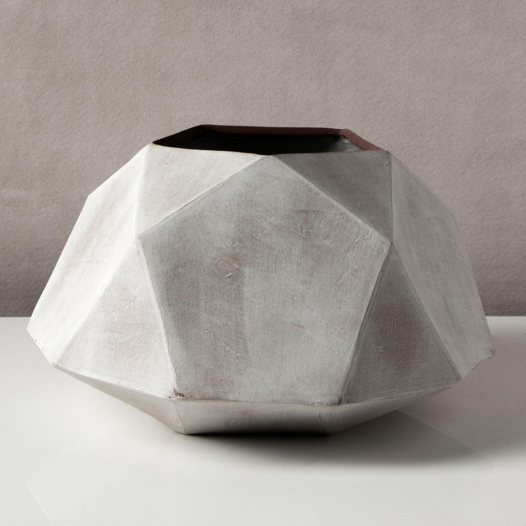 This dramatic ceramic vessel combines clean geometric lines with the warmth and individuality inherent in handmade work; use as a planter or simply as a statement piece. Each vessel is assembled individually from flat sheets of a rich red-brown