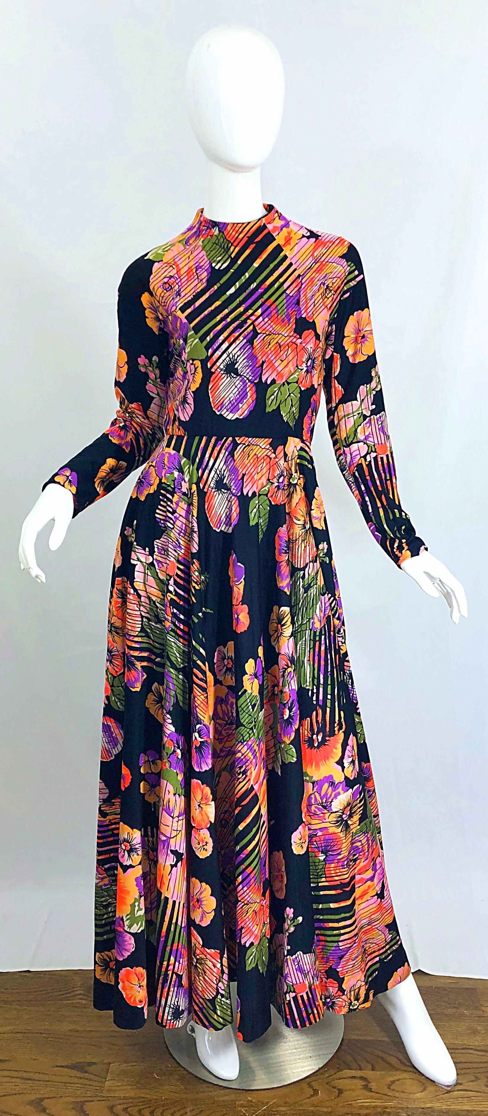 Fantastic vintage 1970s GEOFFREY BEENE abstract flower print long sleeve high neck jersey maki dress. Features floral prints in vibrant colors of purple, pink, peach, orange, green and white on a black background. Super soft double ply jersey