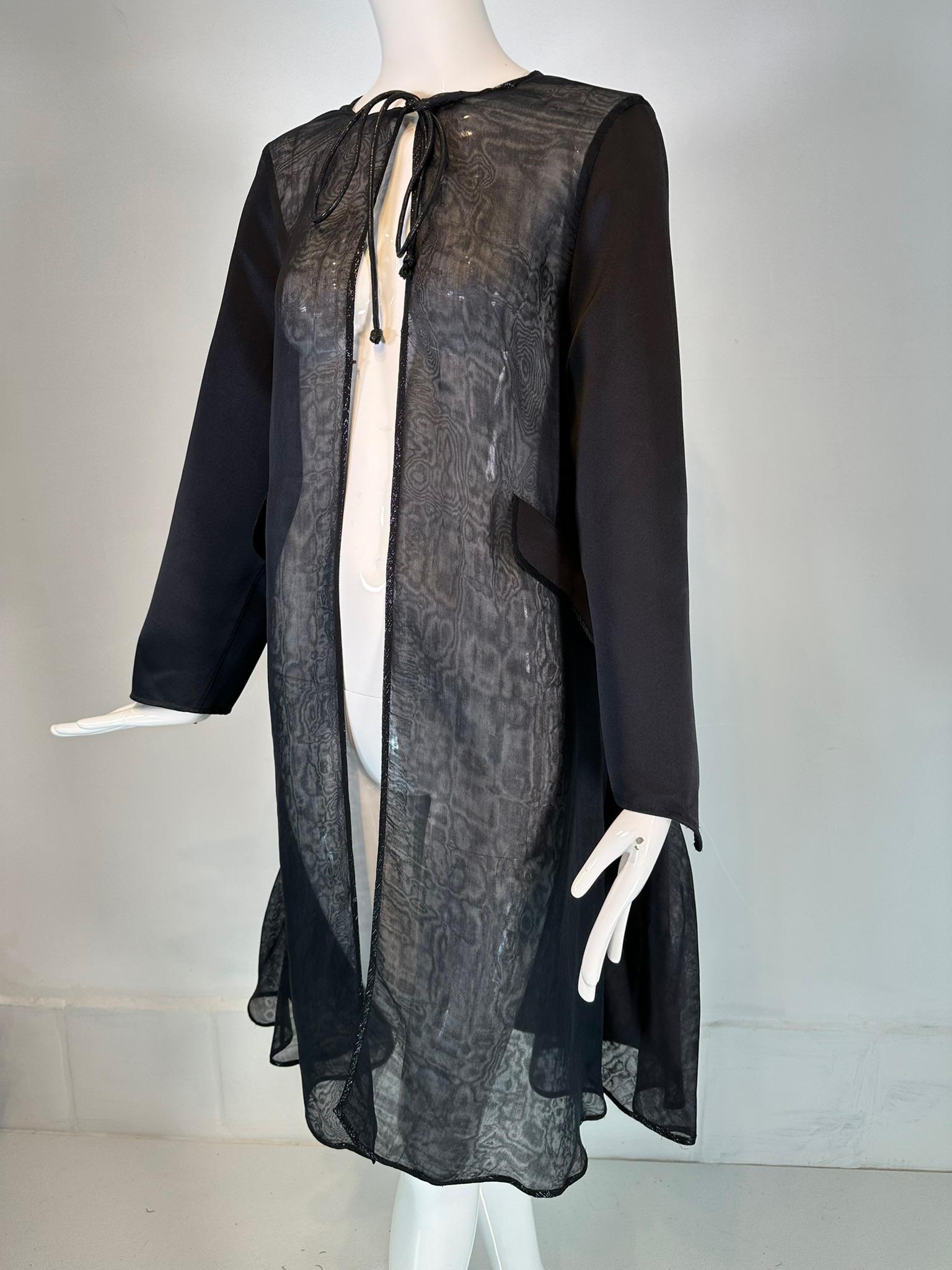 Geoffrey Beene 1990s dramatic black silk satin & black silk organza panel metallic trim tie neck coat.  Unique coat, perfect to add to any look. Long sleeve coat is trimmed in narrow black & silver metallic braid, Lightweight, the coat is open at