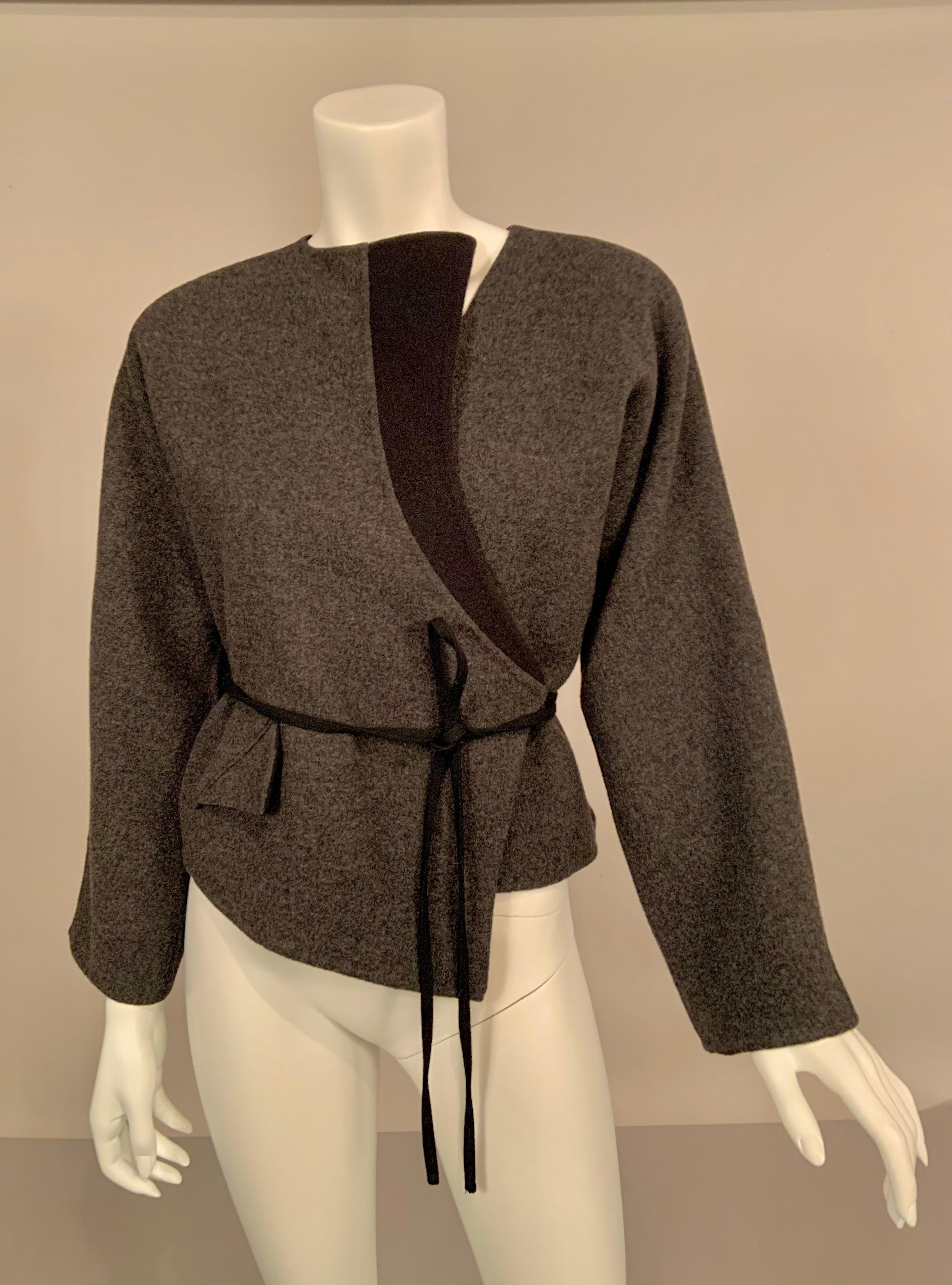 This charcoal grey double faced wool jacket is distinguished by a single lapel which is reversed to the black wool side of the material.  This lapel extends to the black woven cord which wraps around the waist and ties for closure. There is one