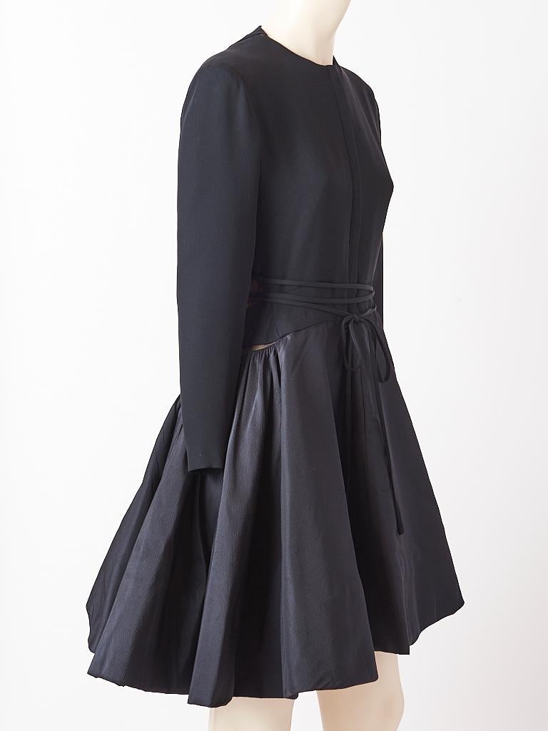Geoffrey Beene, black cocktail dress, having a silk , heavy weight, crepe top and sculpted taffeta faille full, gathered skirt. Dress has a jewel neckline with a hidden front zipper closure. There are asymmetric nude illusion ( black silk tulle over