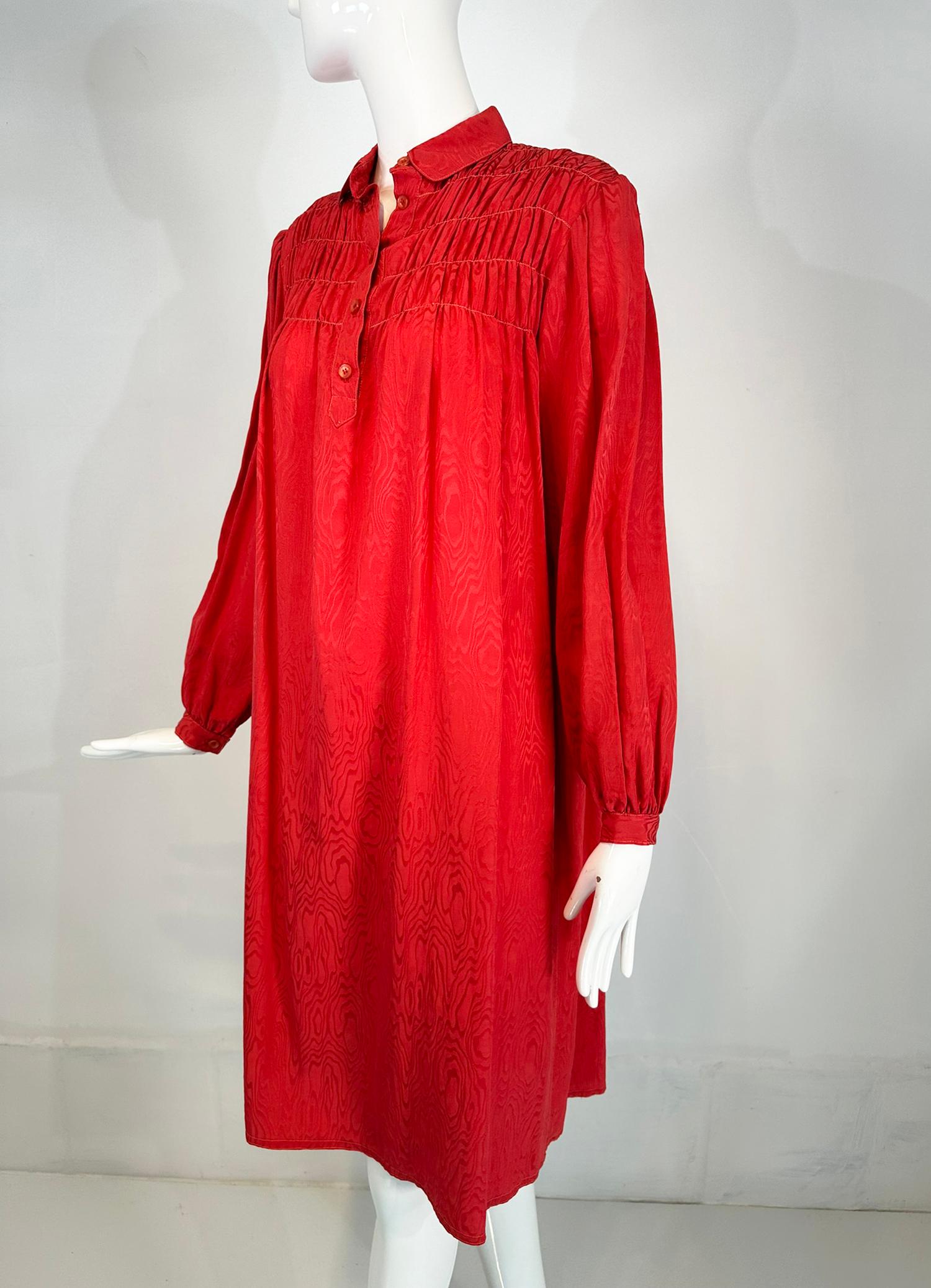 Geoffrey Beene coral red silk jacquard smock dress, from the 1970s. Long sleeve button cuff dress has a Peter Pan collar and button front placket. Gathered shoulder fronts and back give the look of smocking. The dress is semi full. Unlined. Fits