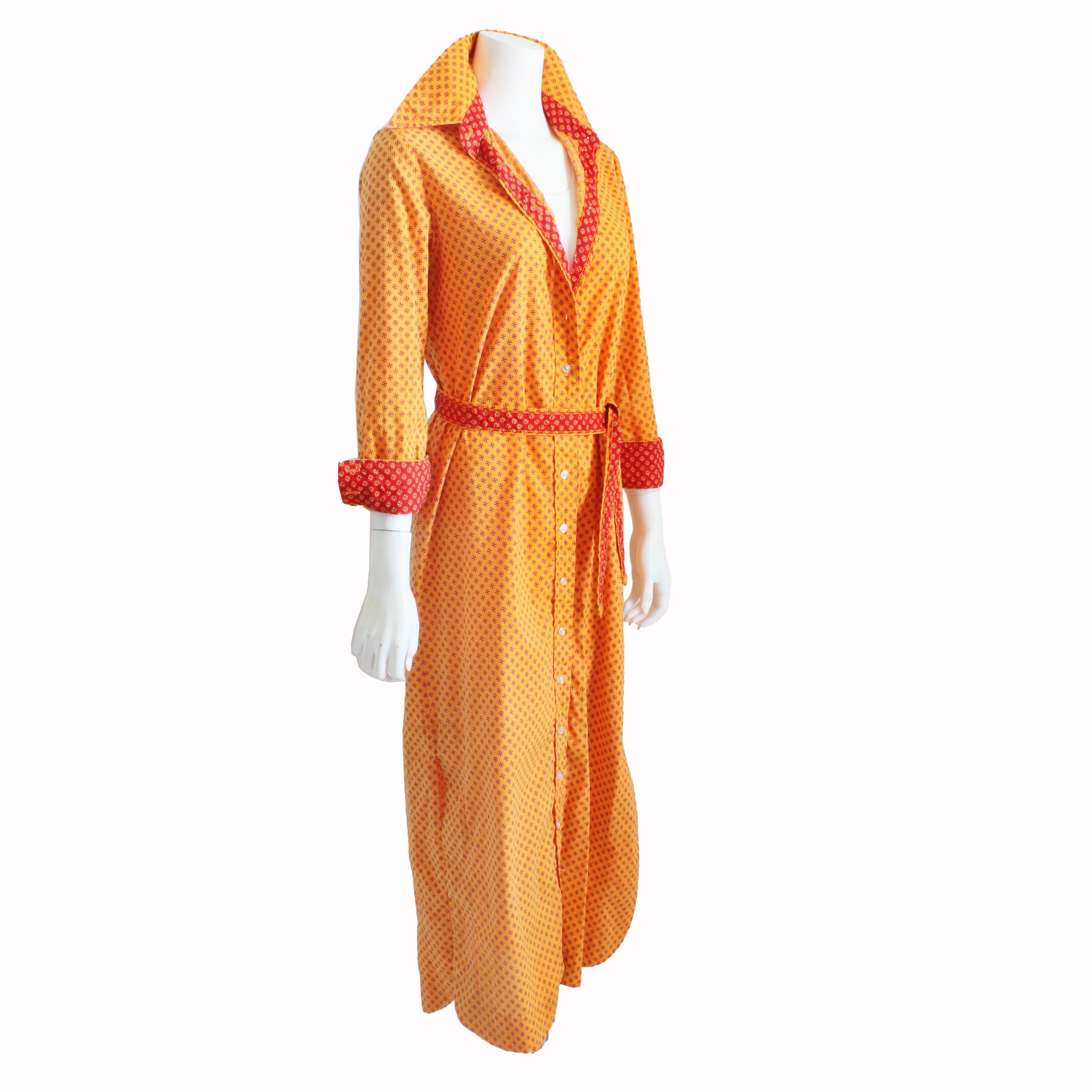 Authentique, d'occasion, vintage Geoffrey Beene robe taille chemise boutonnée avec ceinture assortie, probablement fabriquée dans les années 70.  Fabriqué en coton, il présente un fabuleux imprimé de marguerites orange avec un imprimé rouge