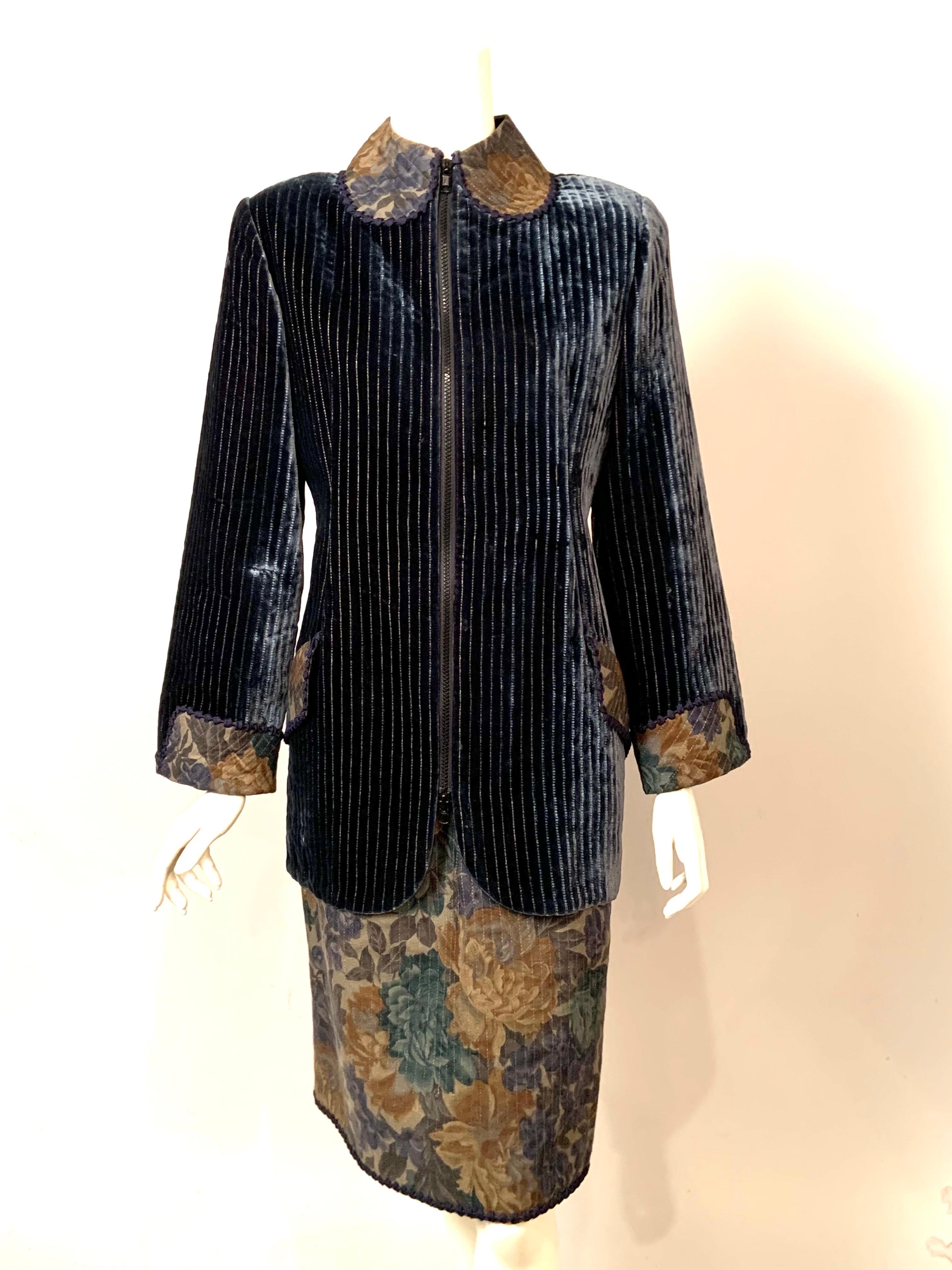 Geoffrey Beene a conçu ce costume en utilisant du velours bleu foncé avec des rayures métalliques en fil d'or sur la veste et la jupe en laine.  La veste en velours a un col rond et des revers de veste, et des rabats de poche dans la laine florale