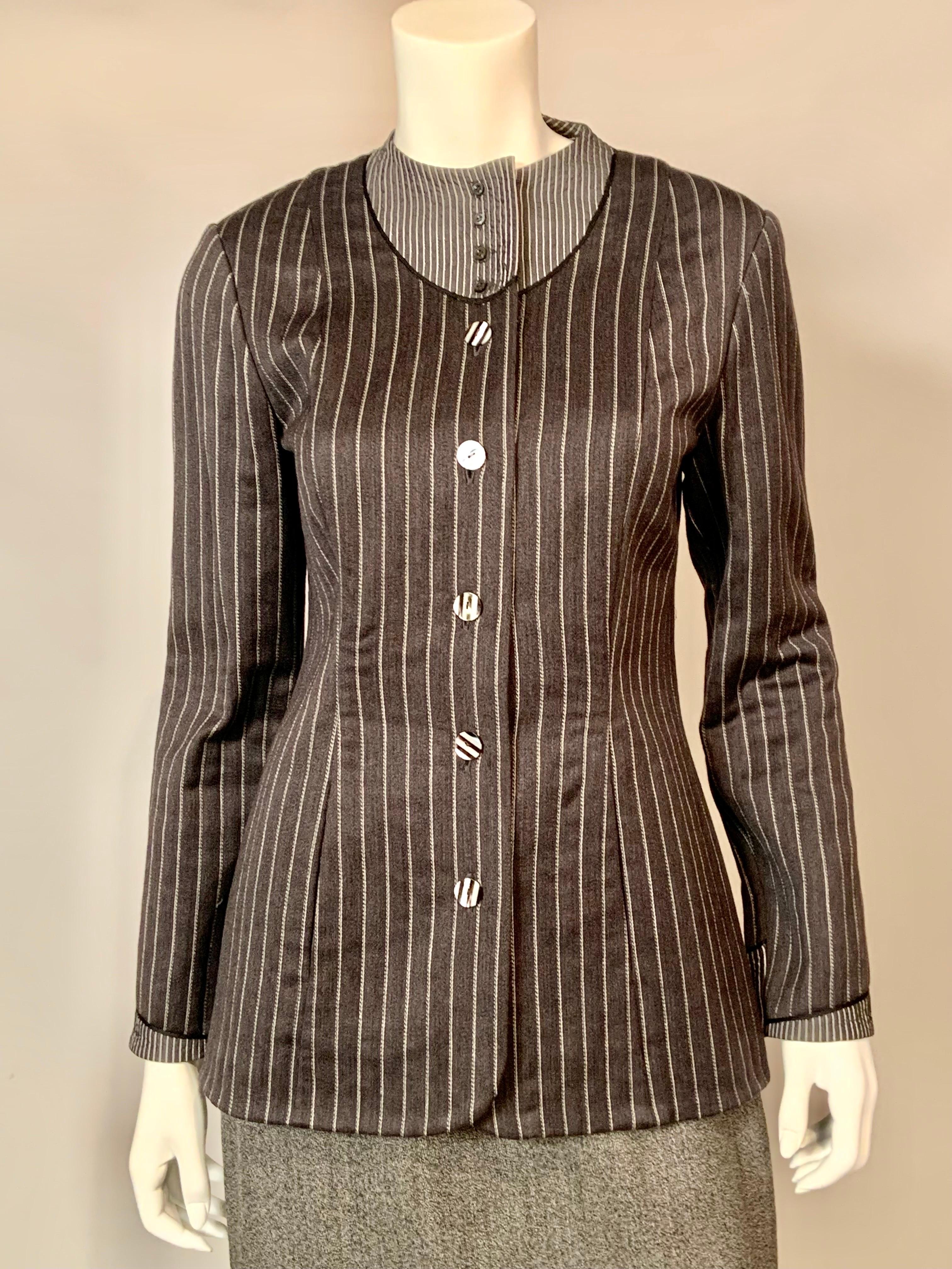 This suit is a stunning example of the work of Geoffrey Beene and his inspired way of using fabrics. The jacket is made from charcoal grey, light weight wool with woven white pinstripes.  The collar and cuffs are grey cotton with a woven metallic
