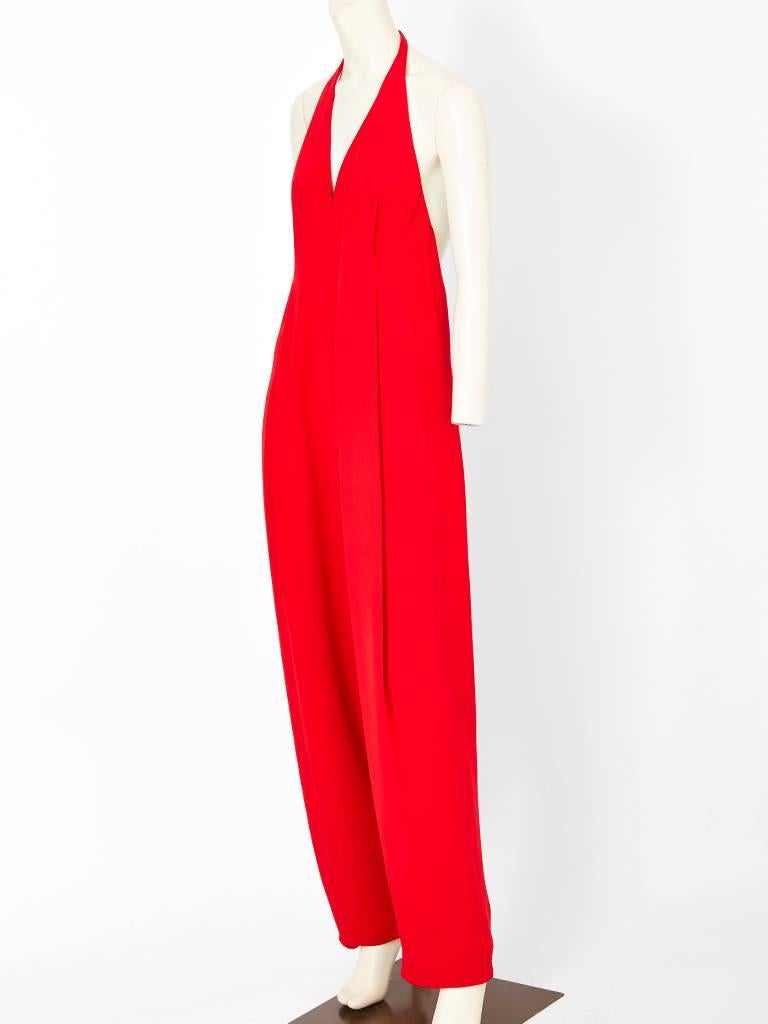 Geoffrey Beene, red, heavy, silk crepe, halter neck jumpsuit, having a deep V in the the front, open back, and a baggy loose fit at the bodice and waist. Trouser legs are wide and taper at the ankle.