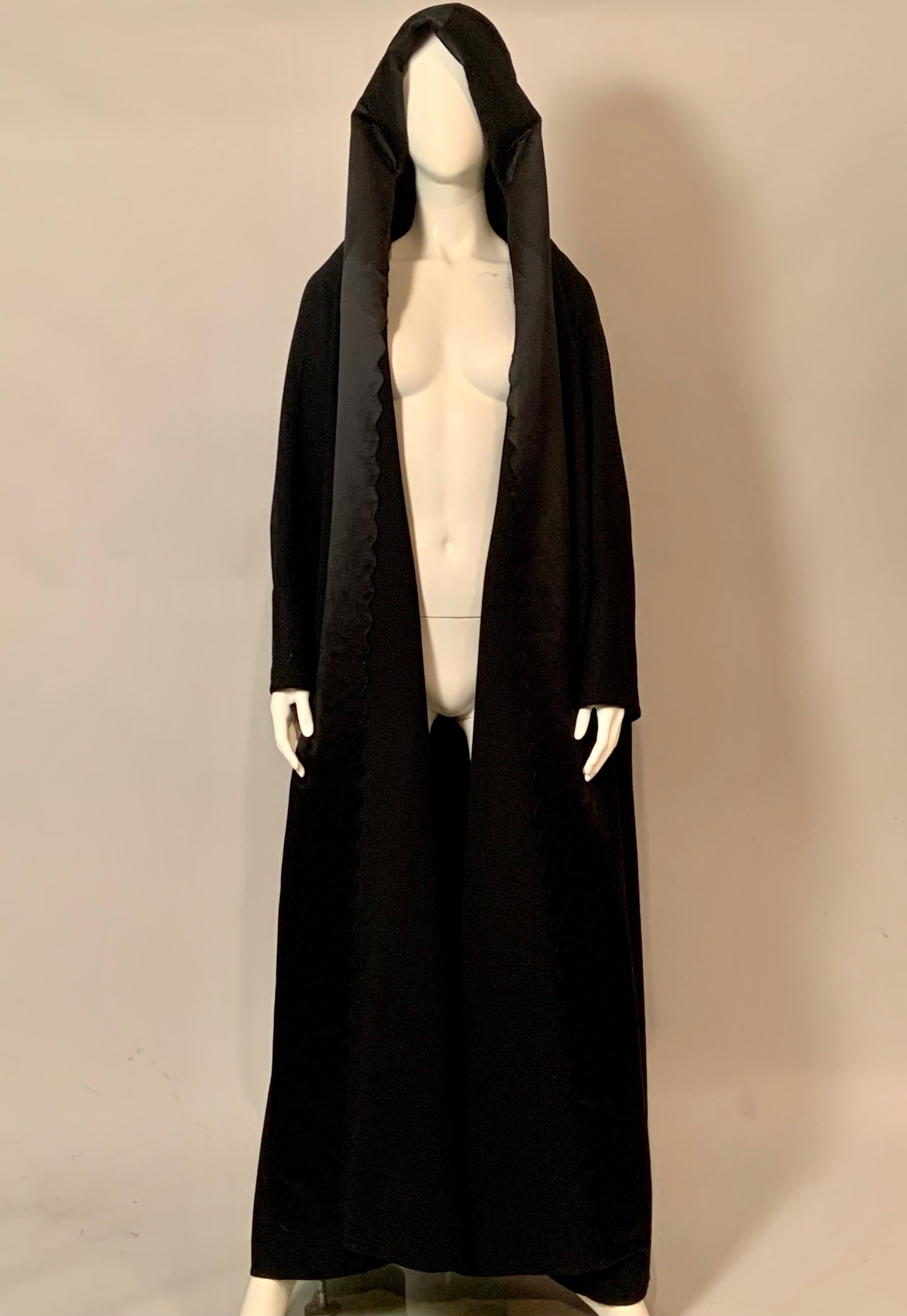 Geoffrey Beene designed a stunning hooded evening coat in his usual spare and elegant style.  This black wool and satin coat has beautiful trapunto stitching on the 
collar, hood and the cuffs and it is scalloped on the interior edge to frame your