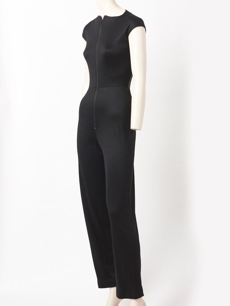 Geoffrey Beene, lightweight jersey, jumpsuit, having a fitted bodice with a middle front zipper closure and a cap sleeve. Back of bodice has a sheer, black, illusion panel exposing the skin. Pant has a straight leg,