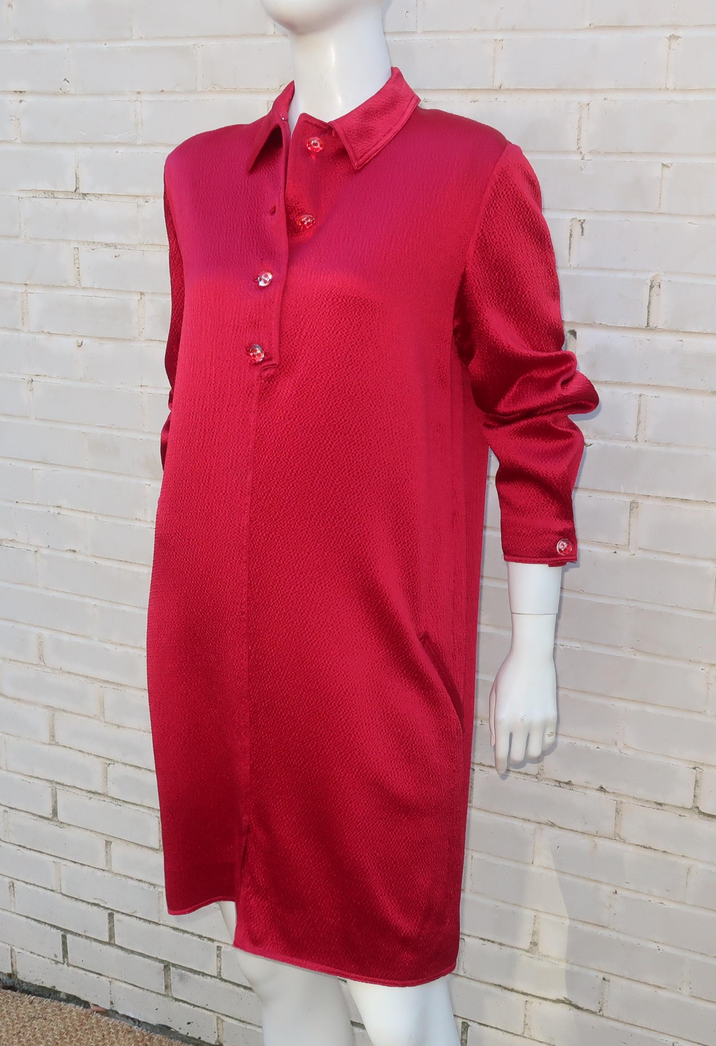 Geoffrey Beene's simple shirt dress design is elevated by a sumptuous textured satin ruby red fabric with metallic threading.  The red dotted lucite buttons add to the glam details which also includes top stitching at the back yoke and a unique cuff