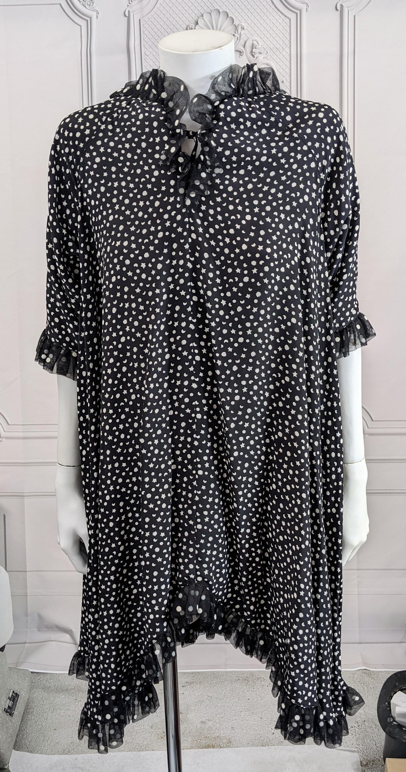 Geoffrey Beene Sillk Crepe Baby Doll Dress trimmed in tulle. Print of white stars and moons on black silk ground with polka dot tulle ruffle edge. Low back cut with gathered silk forming a full tent, fly away shape. Dress shape dips from short to