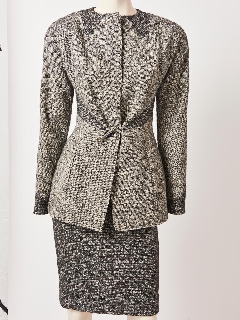 Geoffrey Beene, black and white wool tweed, skirt suit, having black stitching trompe-l'oeil details at the collar and waist. Jacket closes with a tie at the waist, center front  Skirt has the same black top stitching detail as the jacket . Jacket