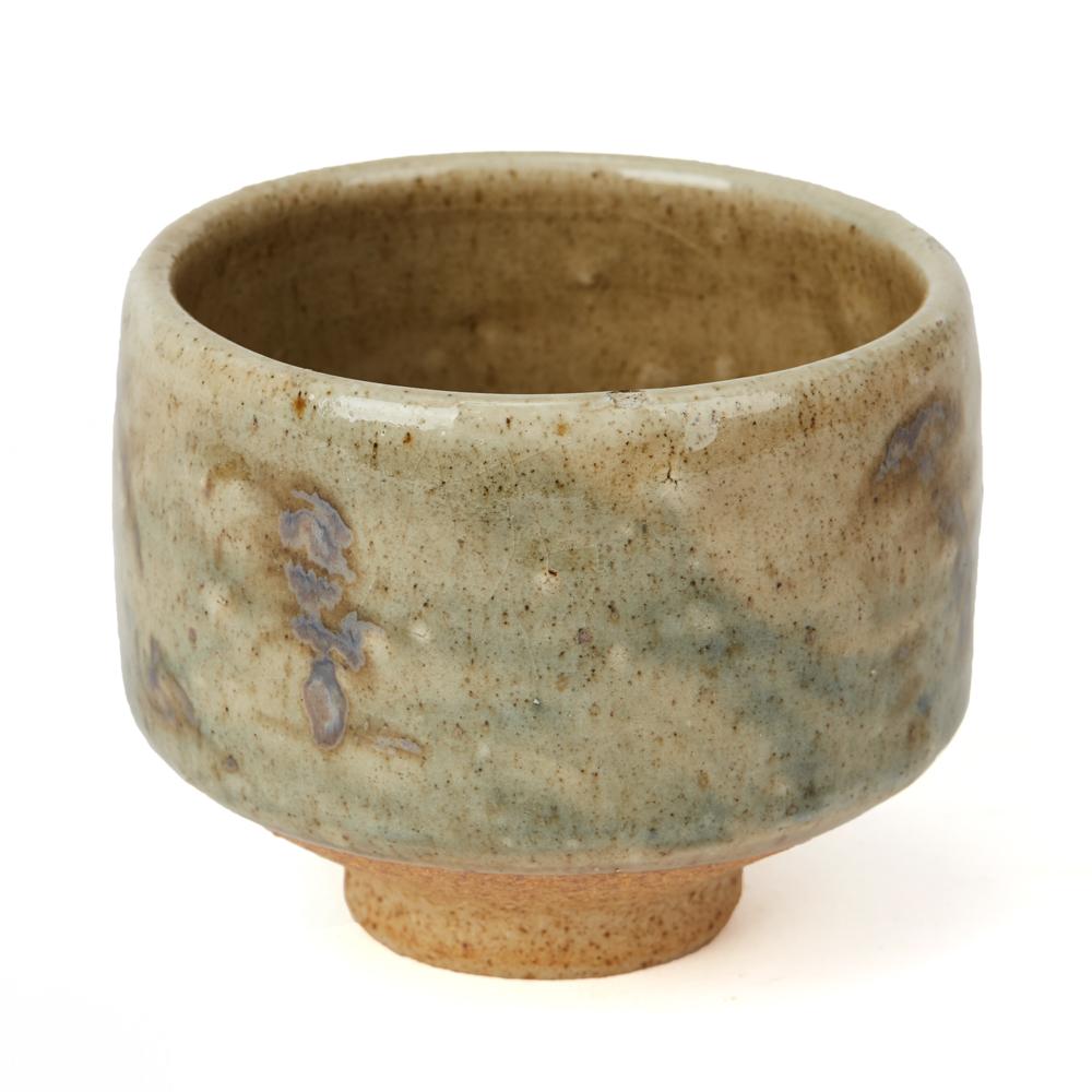 A vintage Studio Pottery chawan made at Avoncroft Pottery by Geoffrey Whiting. The stoneware chawan is of wide rounded form standing raised on a narrow rounded foot and is glazed with feint blue and brown patterns on a grey stone colour glazed