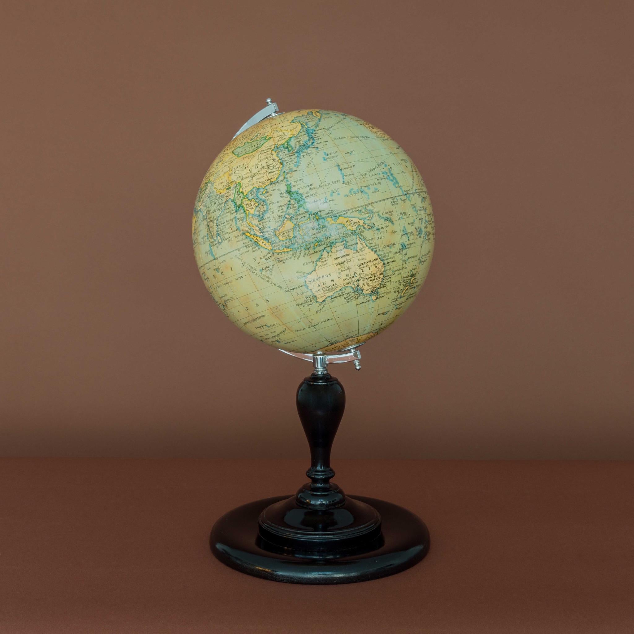 A fine 10 inch terrestrial globe by Geographia of Fleet Street London. With chromed semi-meridian on a turned wooden upright and circular base that has an ebonised finish. Circa 1955. Printed in several colours, the globe comprises of twelve coated