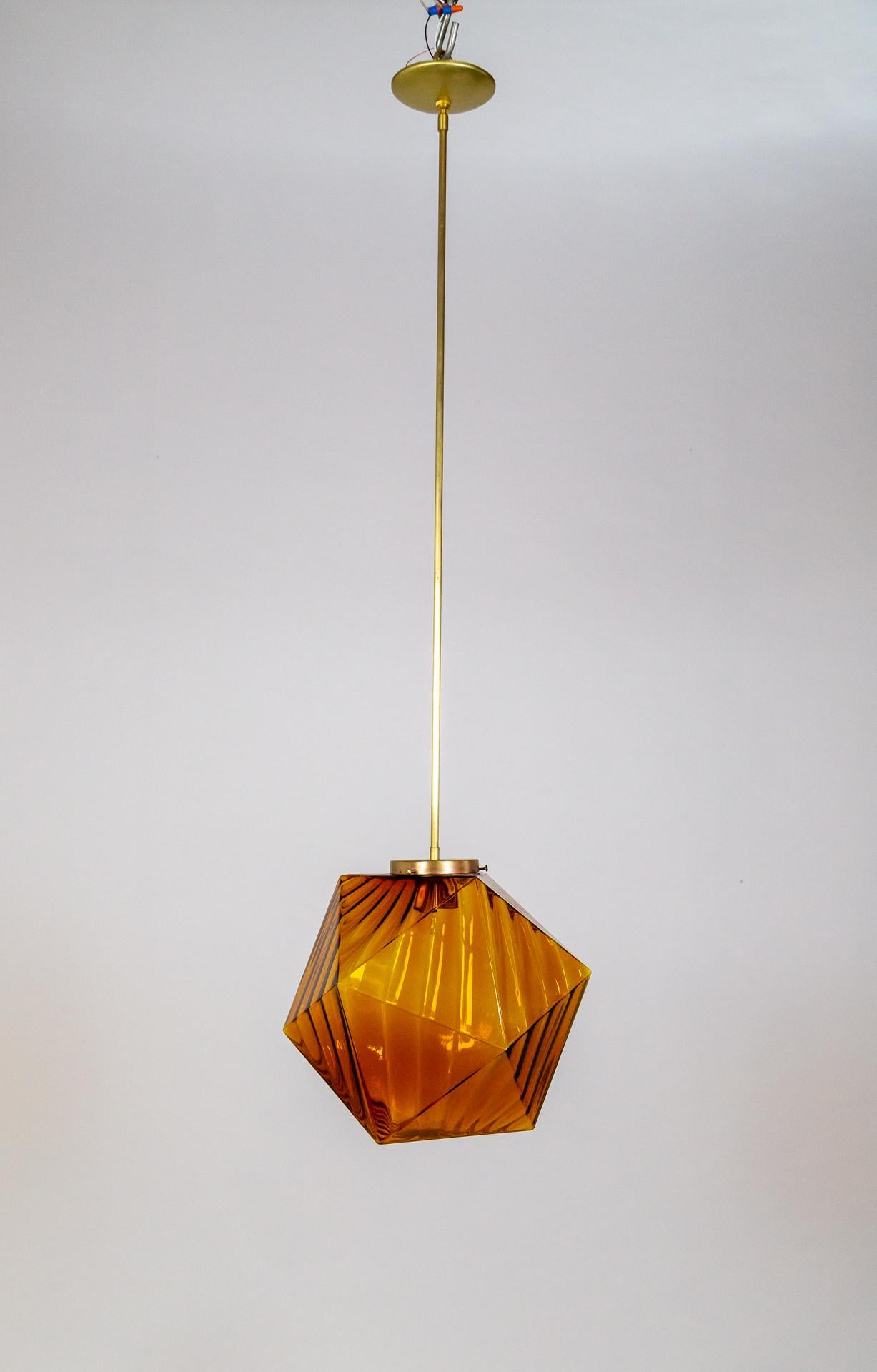 A 1970s pendant light in the form of an icosahedron- a 20-sided polyhedron.  Made of amber-orange glass with a striped effect that has a rippled look.  It has a long, thin brass stem. Newly rewired. 
13