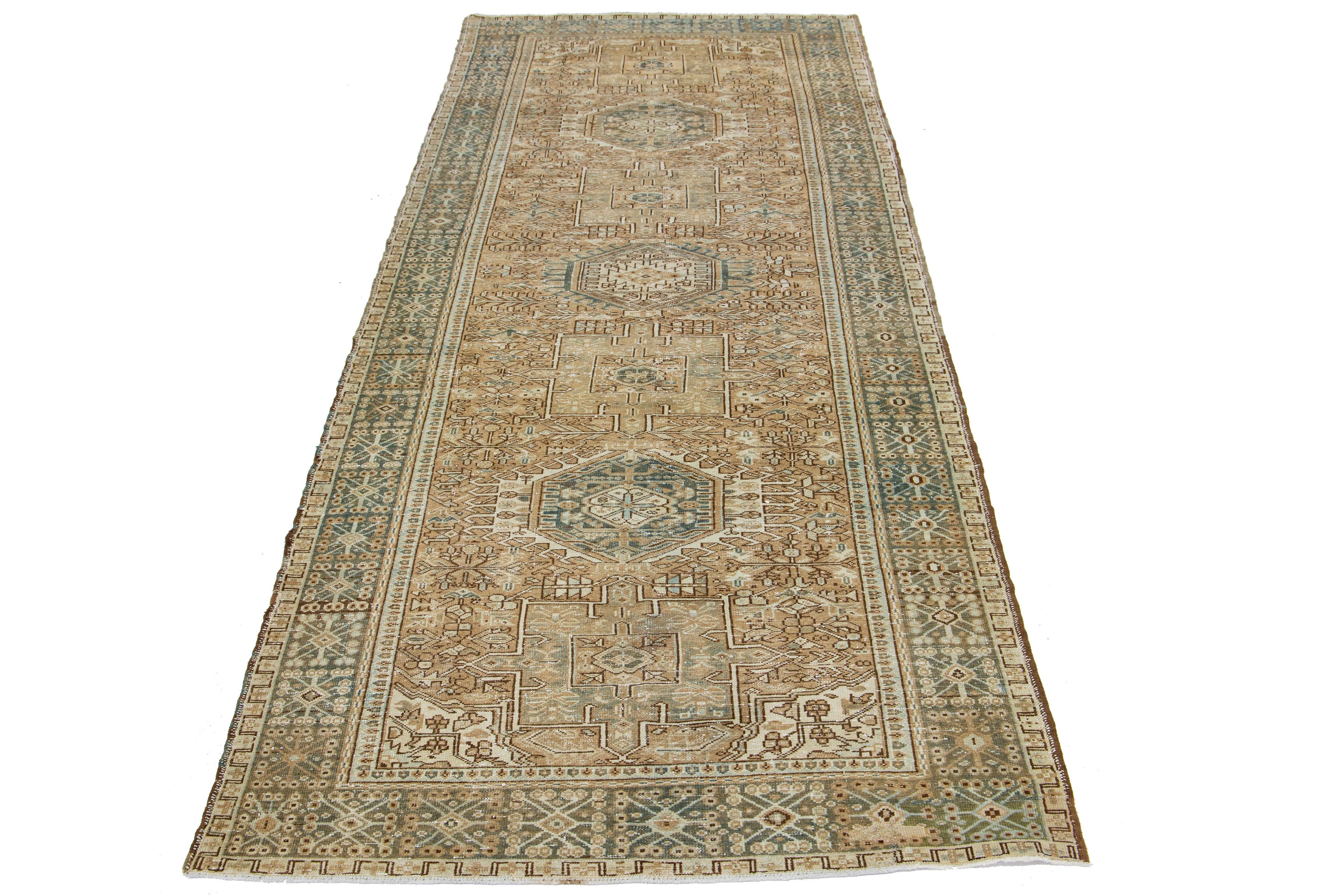 This is a beautiful 20th-century Heriz hand-knotted wool runner with a brown field. The piece boasts stunning blue and beige accents in an exquisite tribal geometric design.

This rug measures 4'9