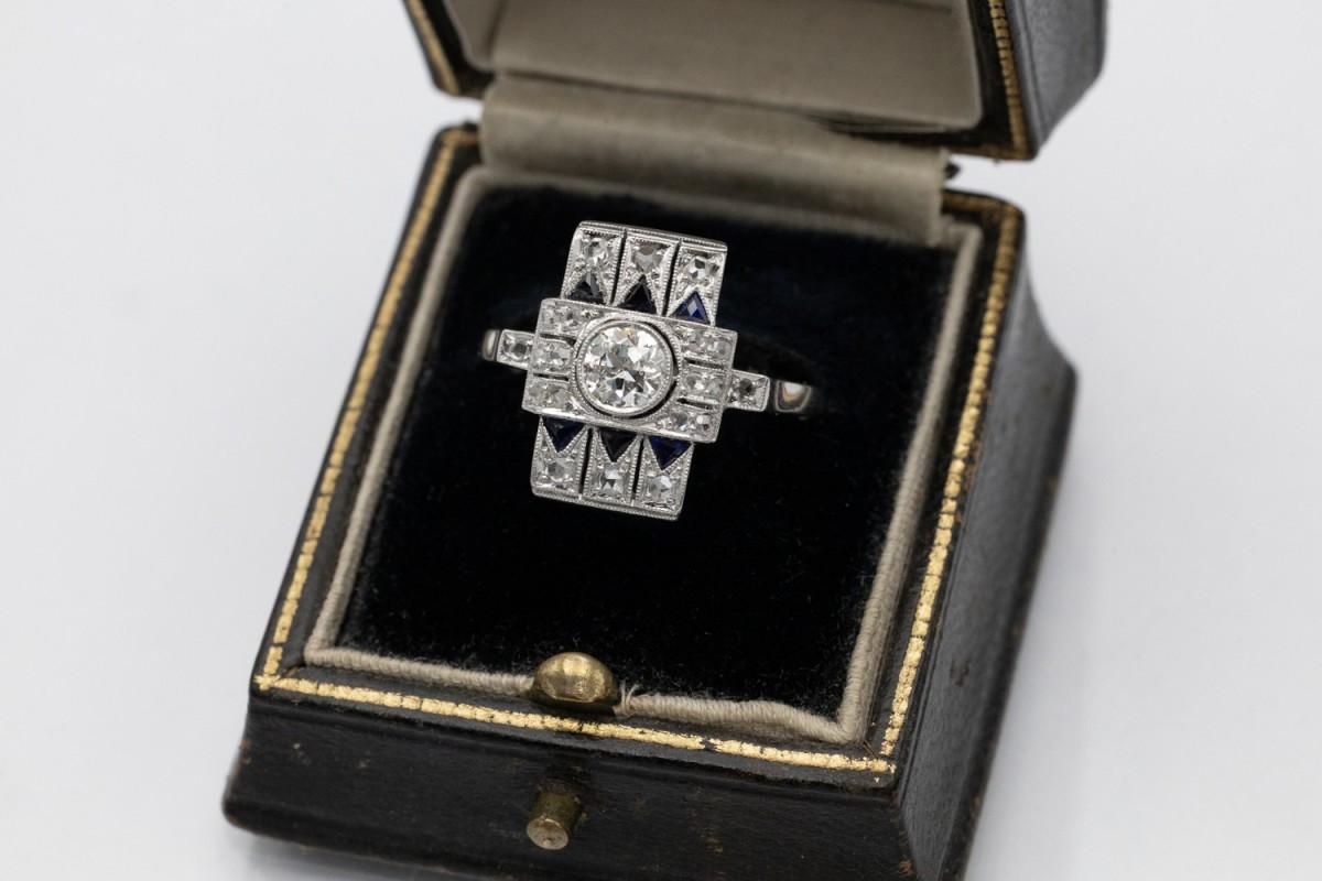 Old ring with a central diamond in an old brilliant cut weighing approx. 0.50 ct (colour I, clarity I1). Additionally, the ring is set with 20 diamonds in a rose cut and triangular synthetic sapphires.

Ring made of 14-karat white gold (0.585