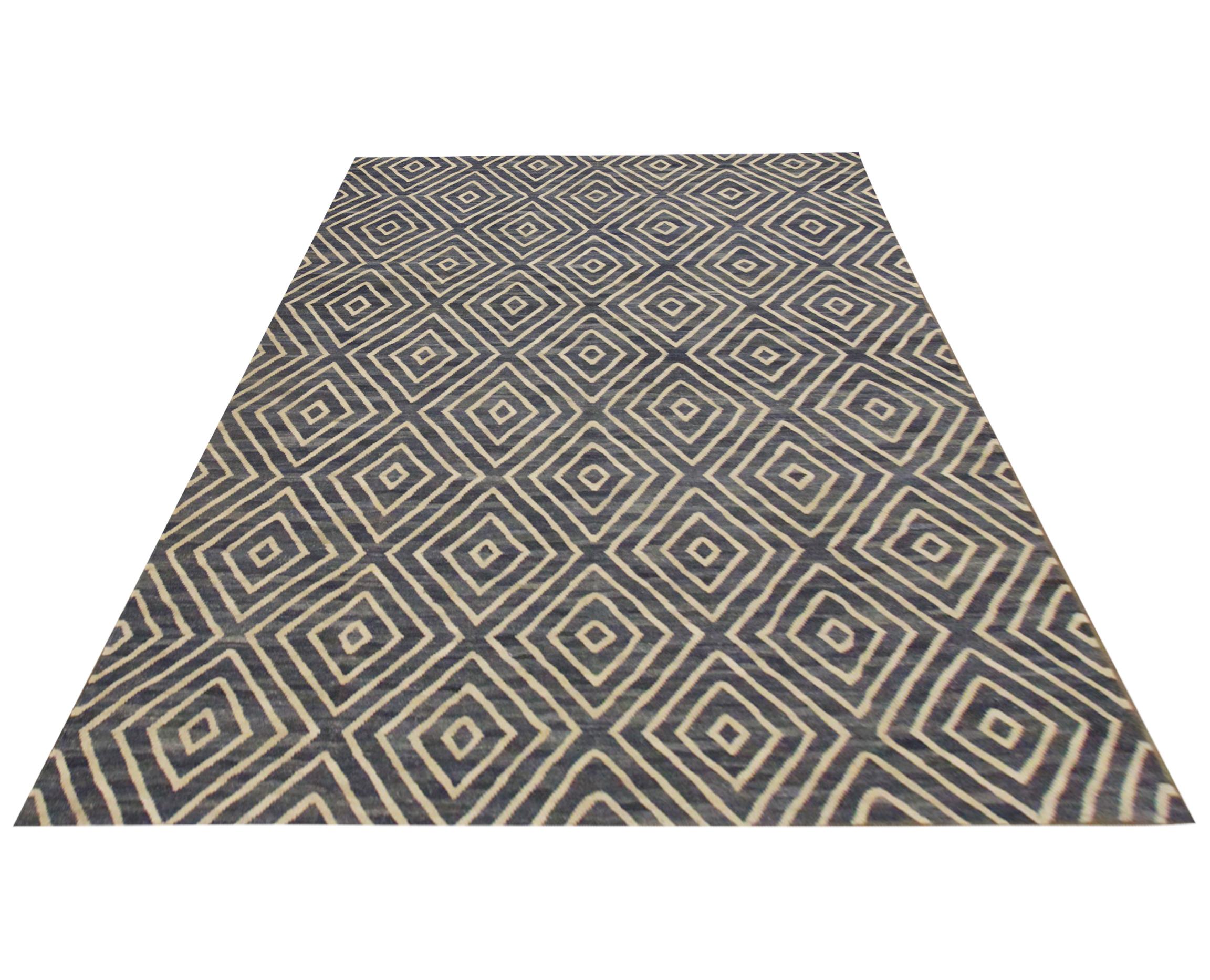 This bold wool area rug is a handwoven Afghan Kilim. The design features an all-over geometric diamond pattern woven in navy blue and cream. The simple, contrasting colour palette and bold geometric design make this piece the perfect accent rug.