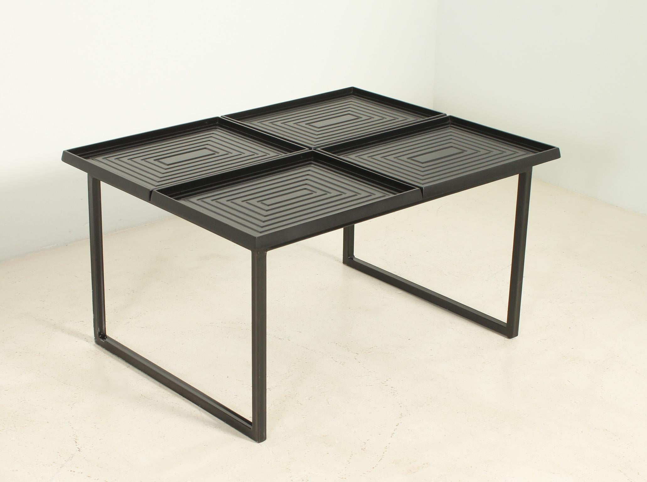 Rare coffee table from 1980's composed by four loose trays in lacquered wood with geometric carved relief on a black lacquered metal base.