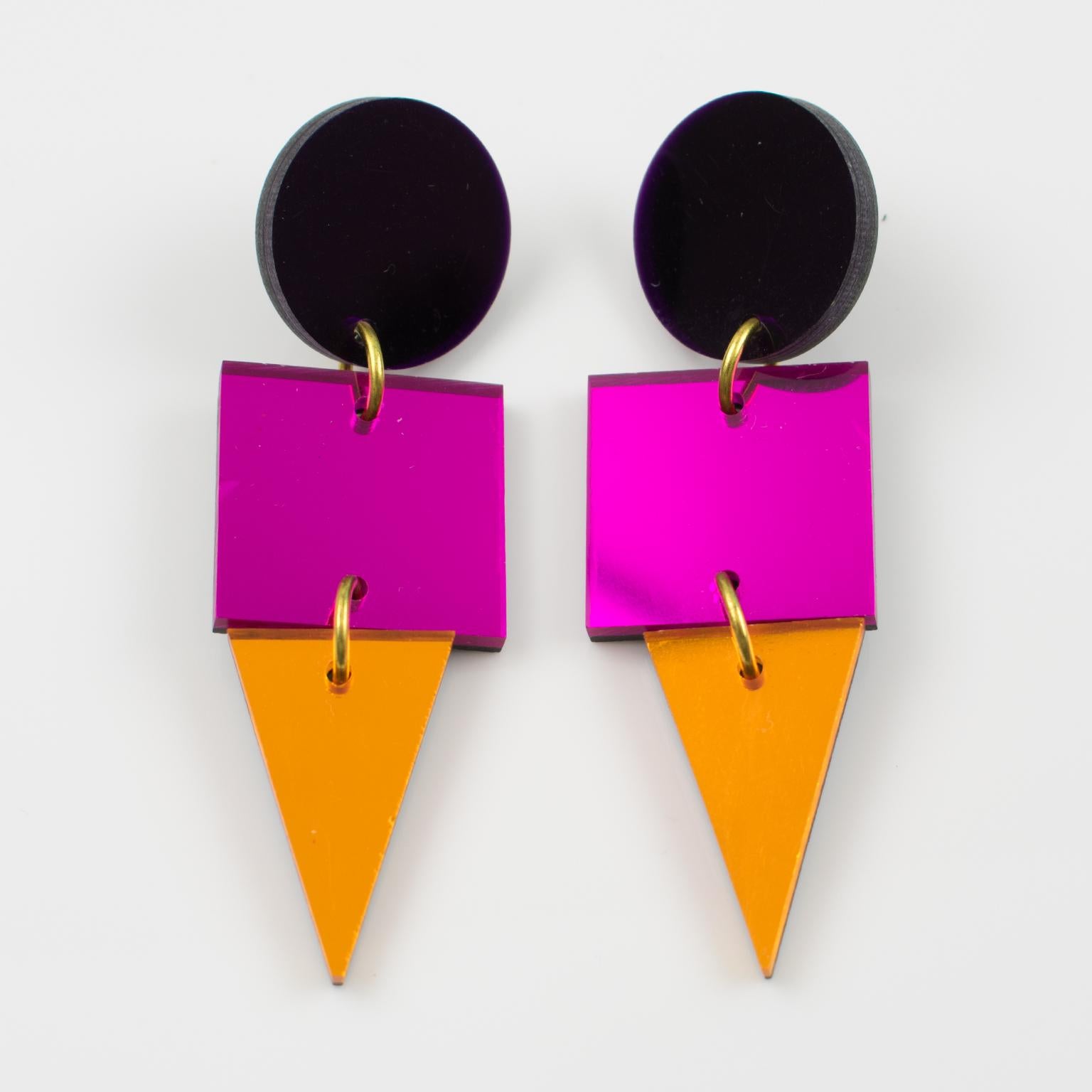 Ces magnifiques boucles d'oreilles en Lucite ou en résine présentent une forme géométrique plate avec des couleurs colorées et des motifs texturés en miroir dans les tons orange néon, rose vif et violet. Ils sont destinés à des oreilles percées,