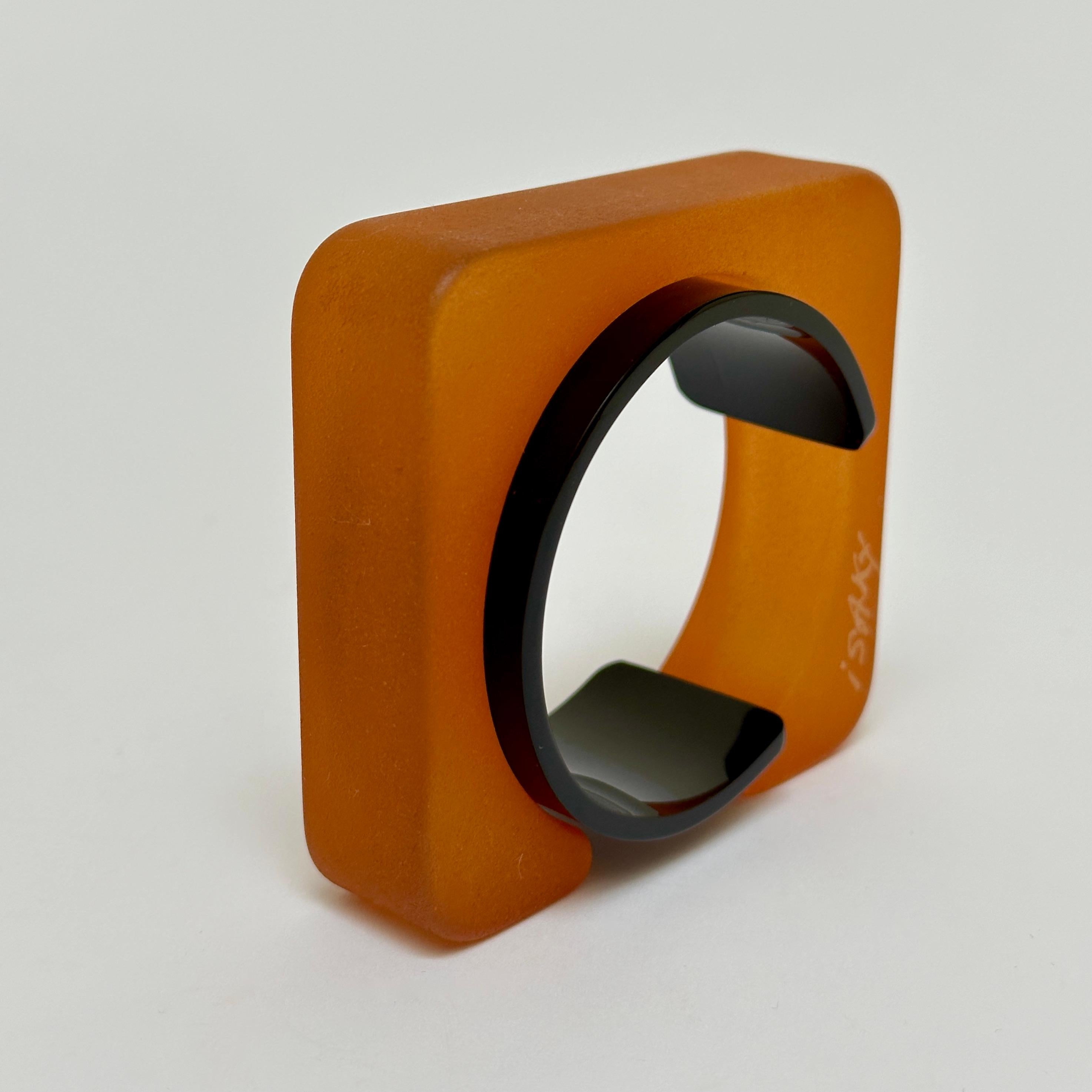 Half object, half jewel this sculptural bangle is composed of two parts ; a sand blasted resin rectangle and an acrylic bracelet allowing the cuff to be closed.
The bangle bears the handwritten and engraved signature of the artist.

Measurements