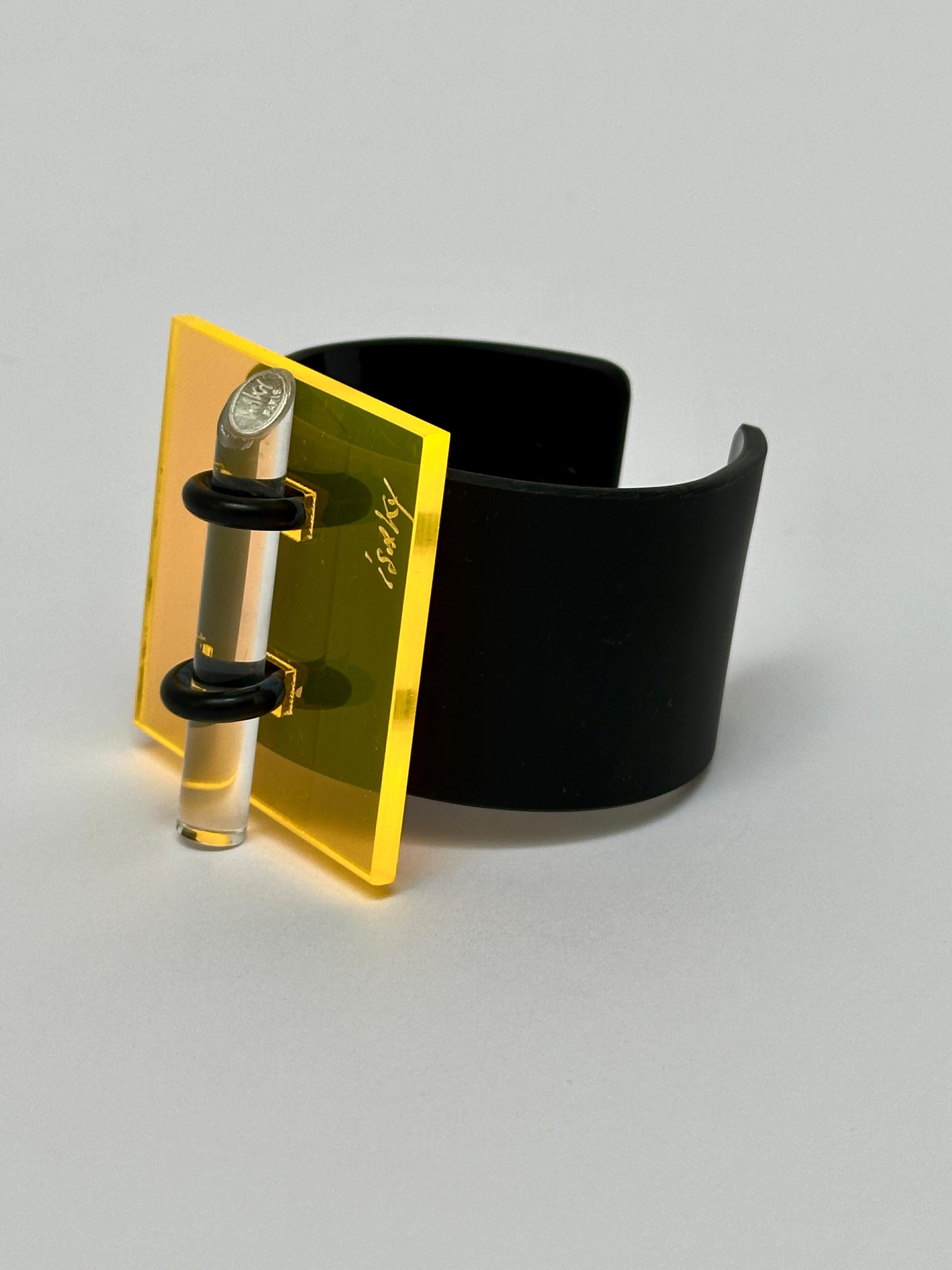 Methacrylate plate fixed by a rubber link on a black acrylic bracelet, matt exterior and glossy interior, locked by an altugas rod wearing the Artist's brand.

Both the facade and the bracelet are hand signed.

Measurements (cm) 
square 5.3 x