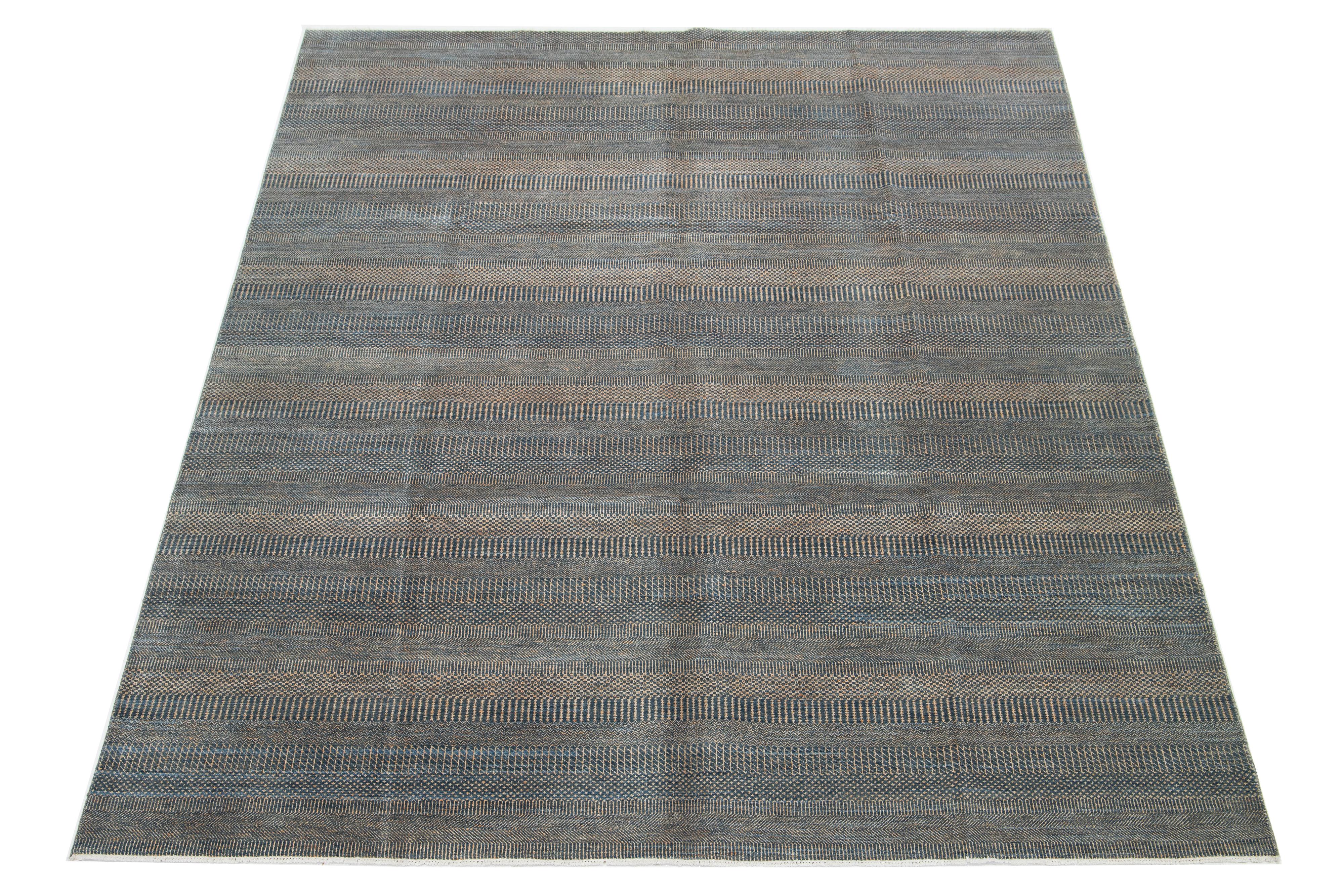 Questo splendido tappeto in lana annodato a mano presenta un design moderno. Mostra un campo accuratamente lavorato nei toni del grigio, del blu e del ruggine, ornato da intricati motivi geometrici.

Questo tappeto misura 9'2