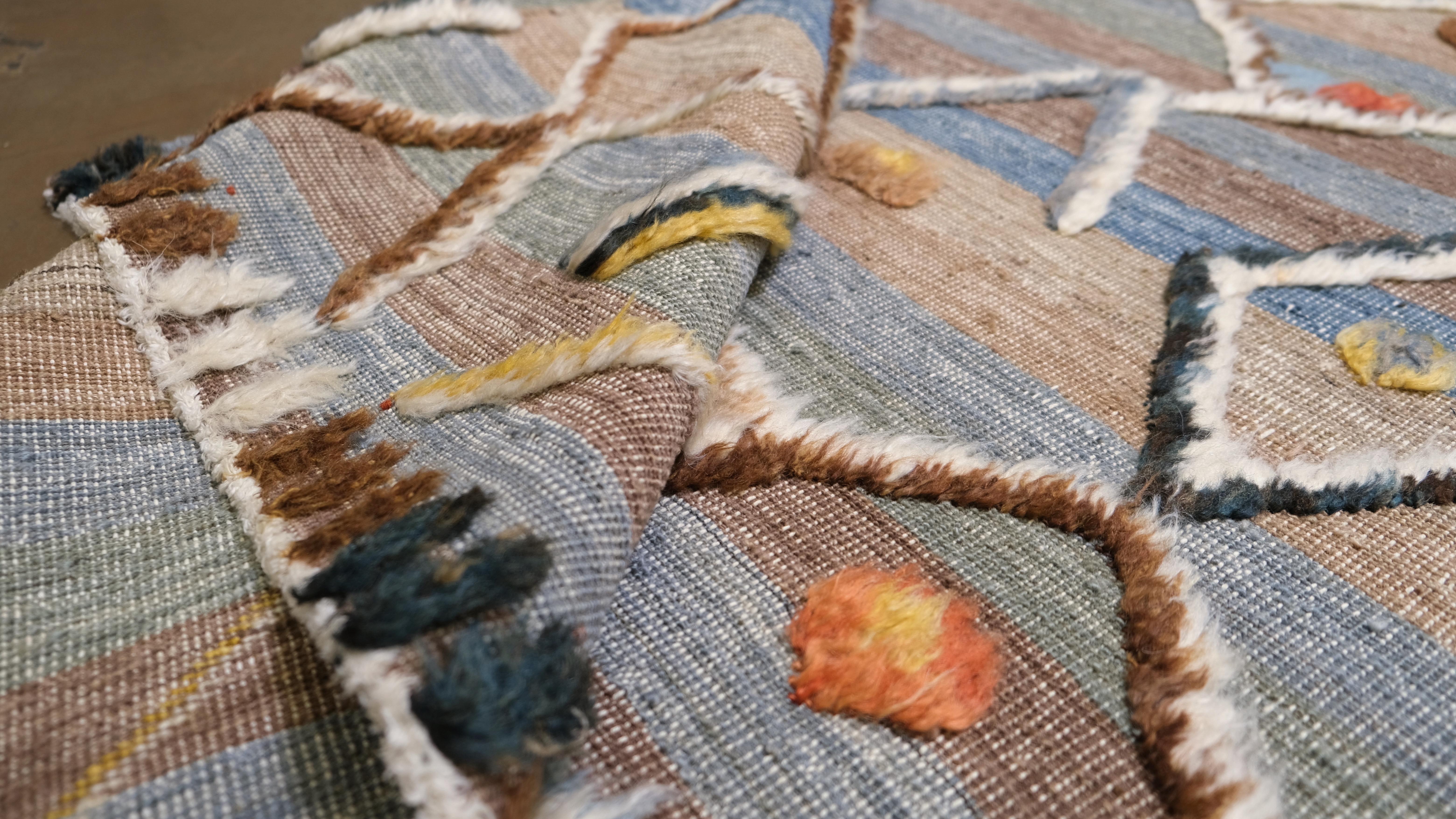 Infuse your interior with the vibrant charm of this hand-knotted wool rug, featuring an intricate geometric tribal pattern. The multicoloured palette incorporates warm tones of orange, yellow, blue, and earthy browns, creating a lively yet