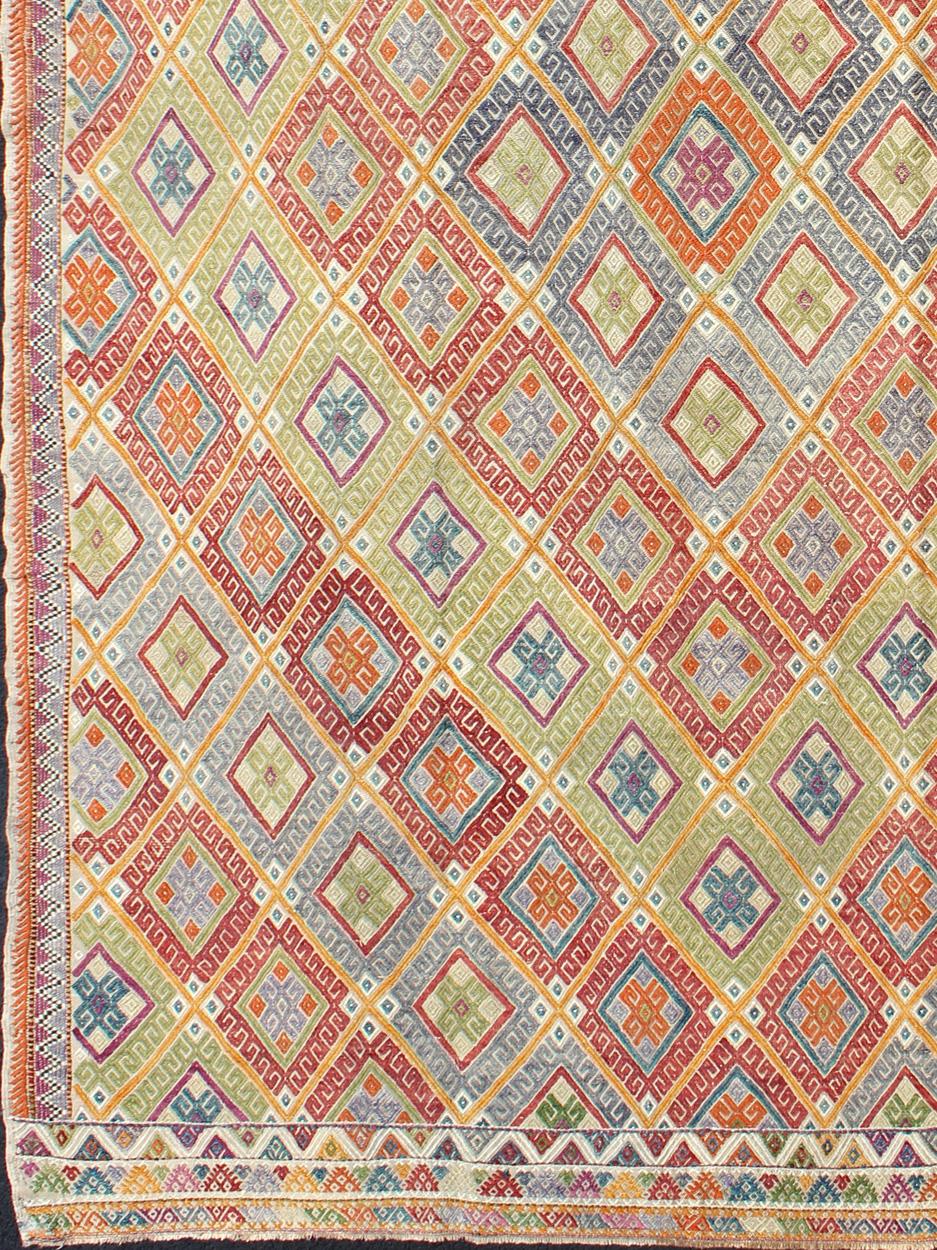 This geometric Kilim from Turkey bears a repeating large diamond design consisting of patterns of smaller, intricate, geometric shapes. The repeating design has wonderful colors in red, green, orange, ivory, and blue.

Measures: 6'5'' x
